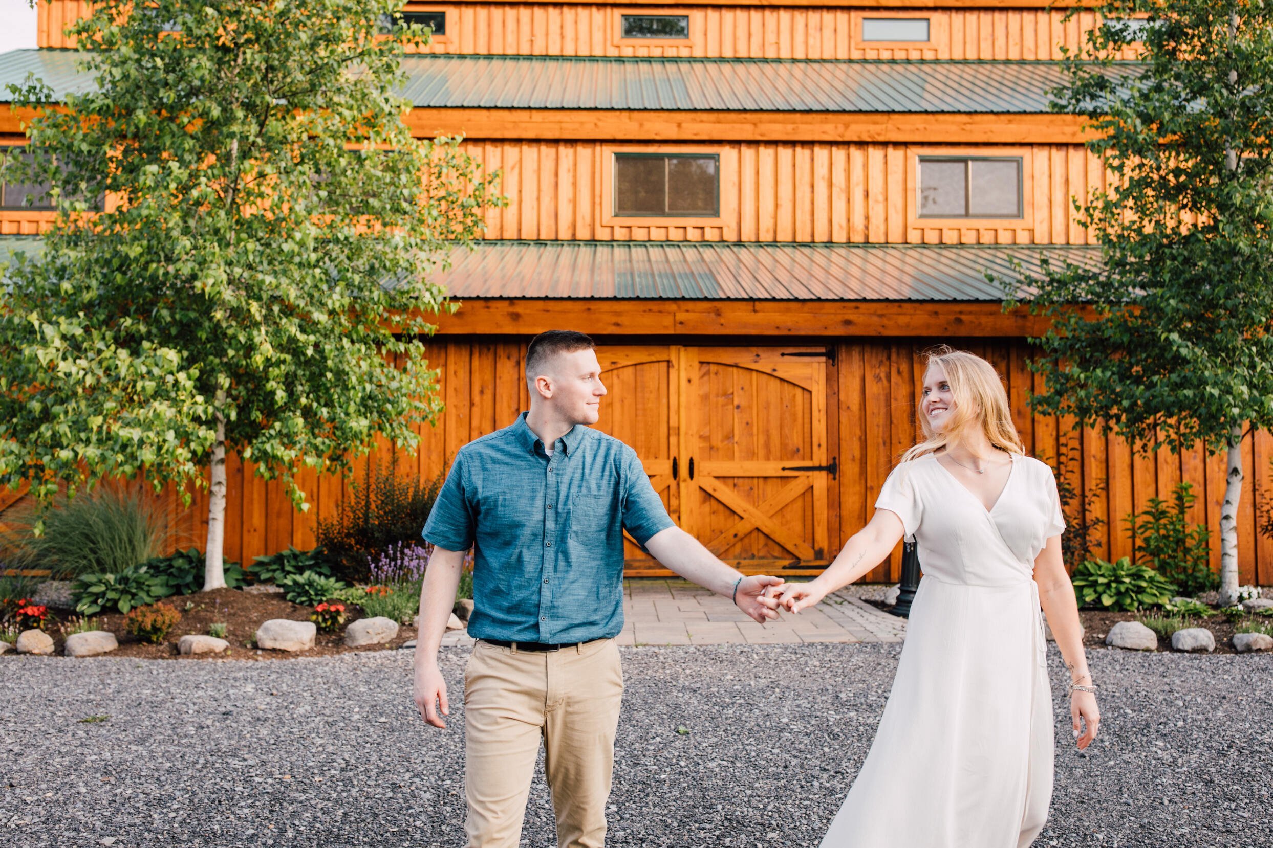  Engaged couple swing their entwined hands in front of a barn during their farm engagement photos 