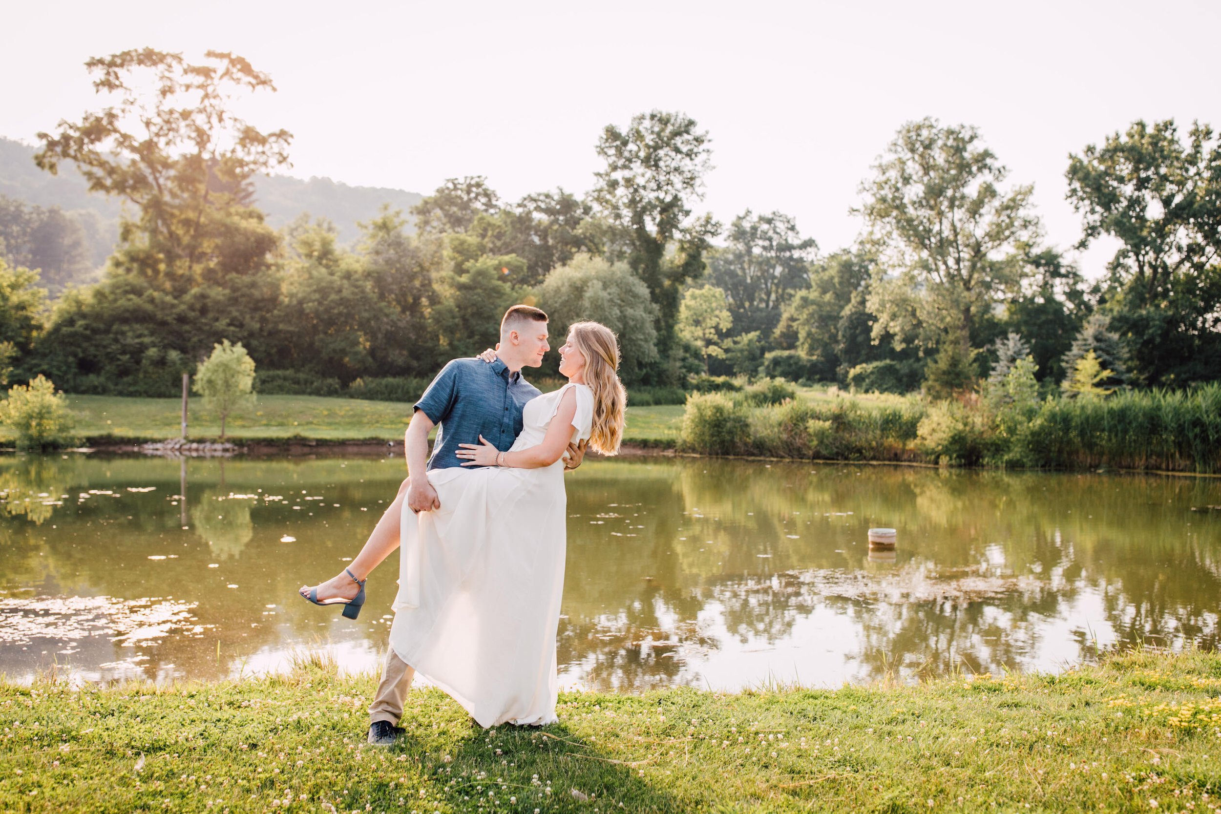  Jake leans his fiancé back while looking at her in front of the pond at rocking horse farm 