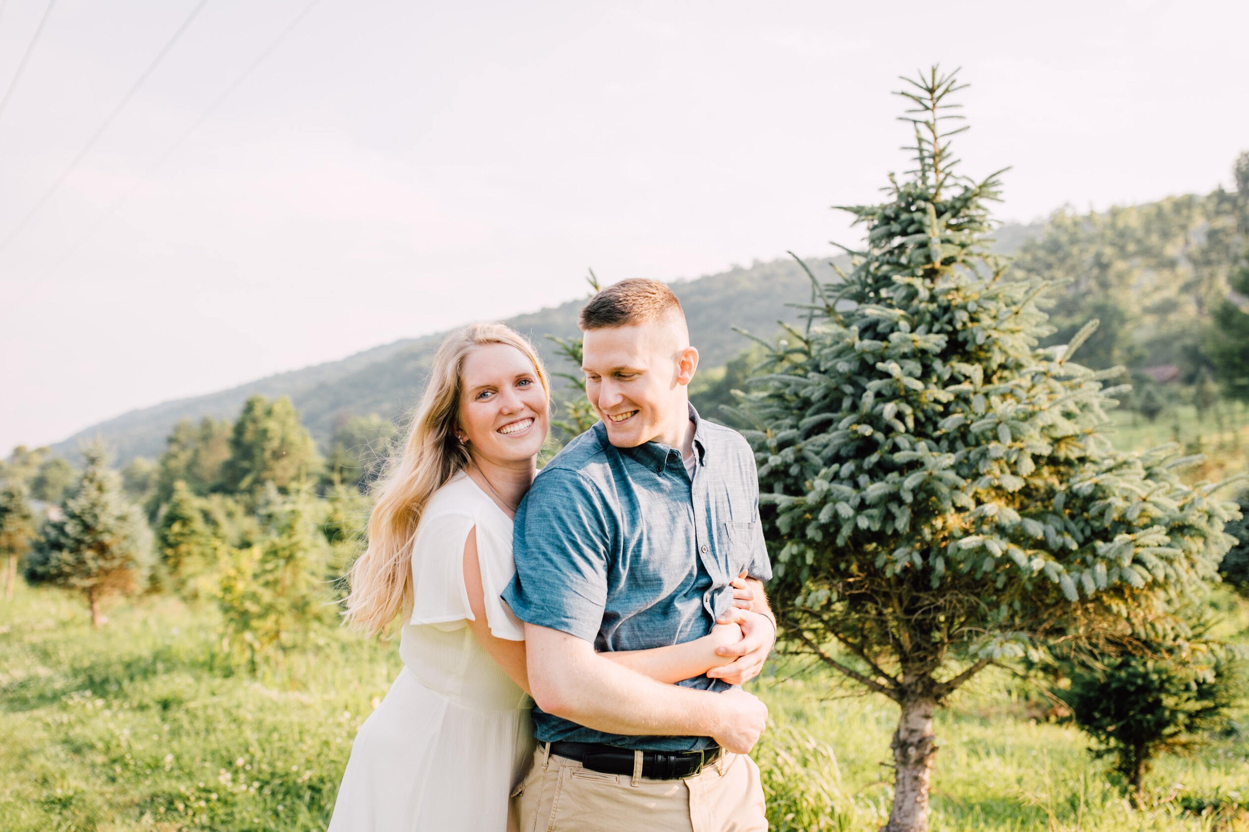  Engaged couple smile together during engagement Christmas tree farm photos 