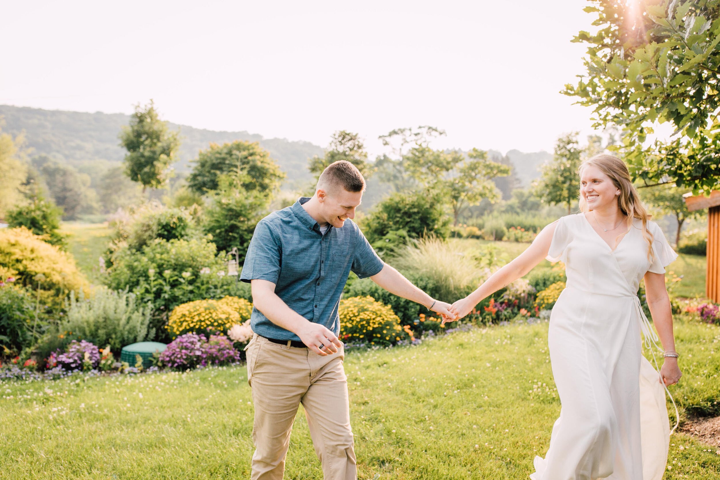 Engaged couple laugh together while holding hands for their farm engagement photos 