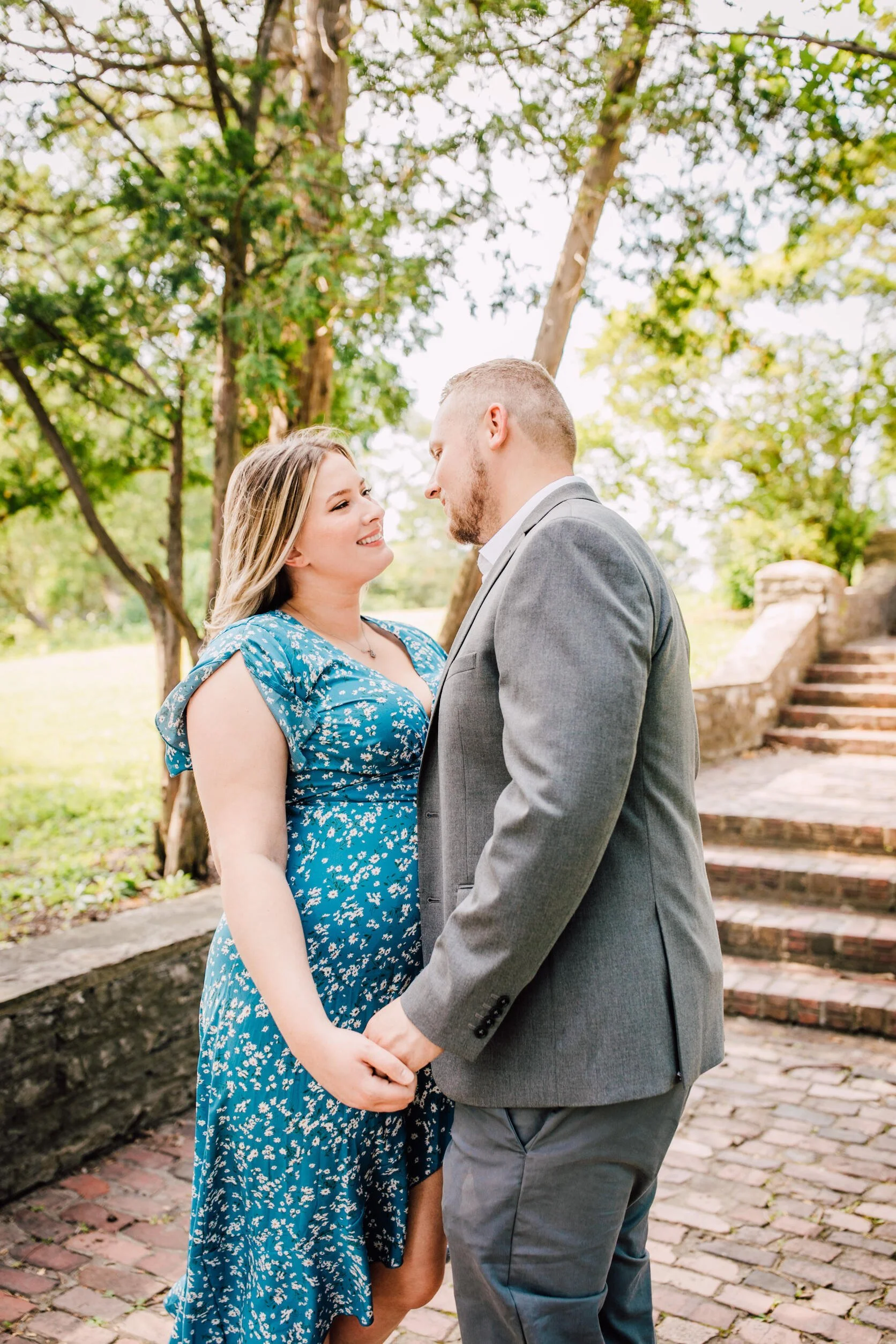  Woman looks at her fiancé while holding his hand for their garden engagement photos 