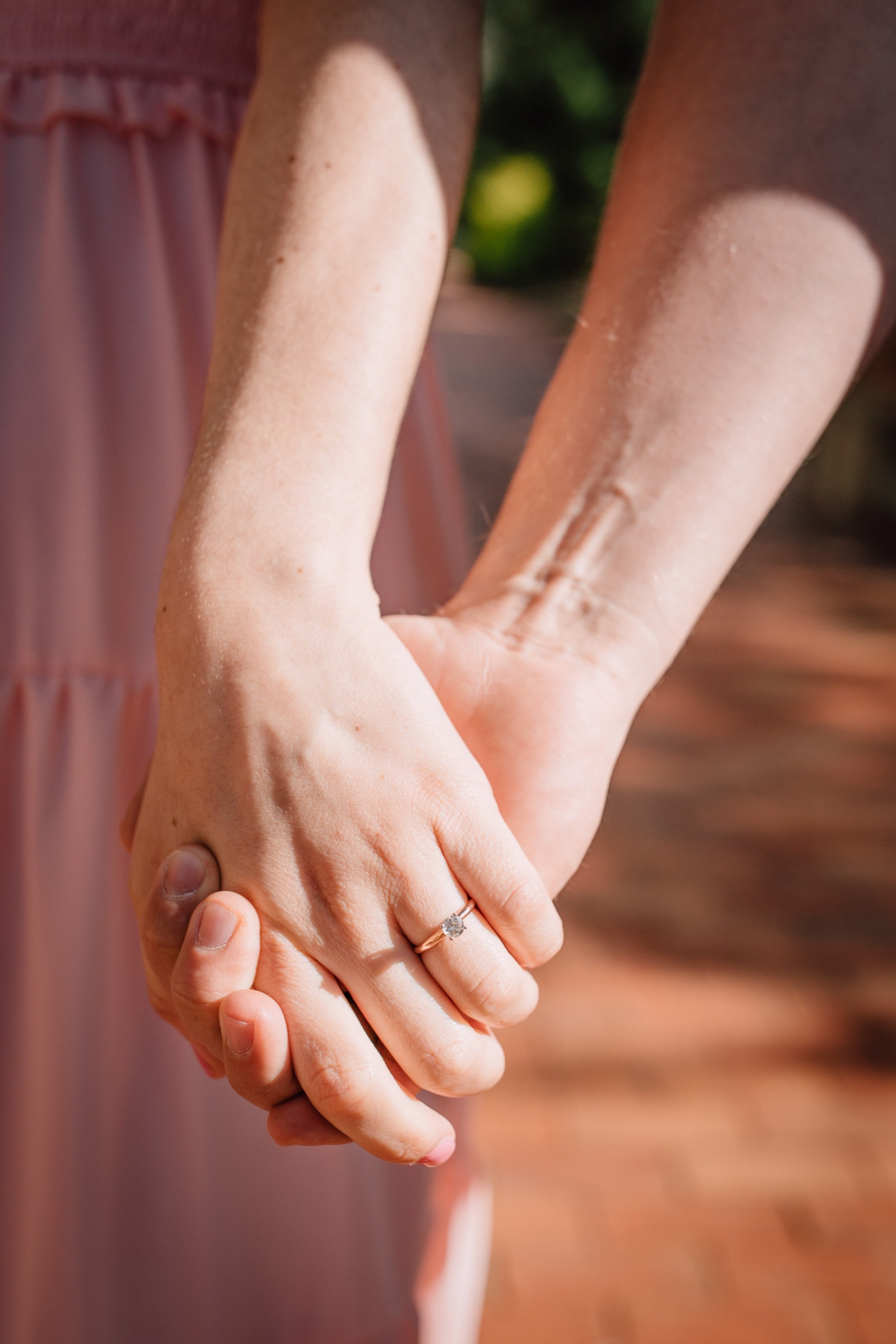  engaged couple hold hands to show off the engagement ring during engagement photography session 