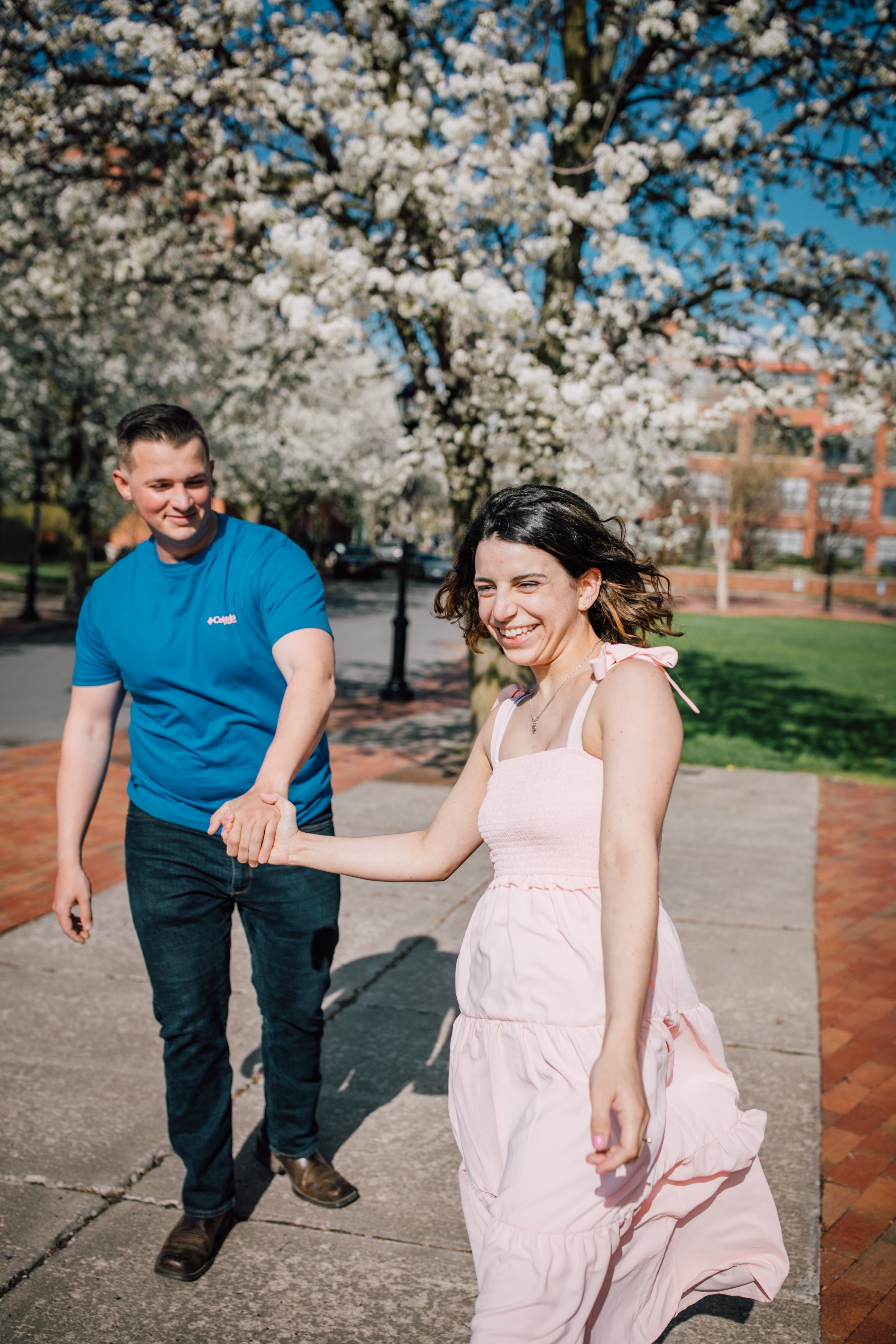  engaged couple laugh while walking during engagement photography 