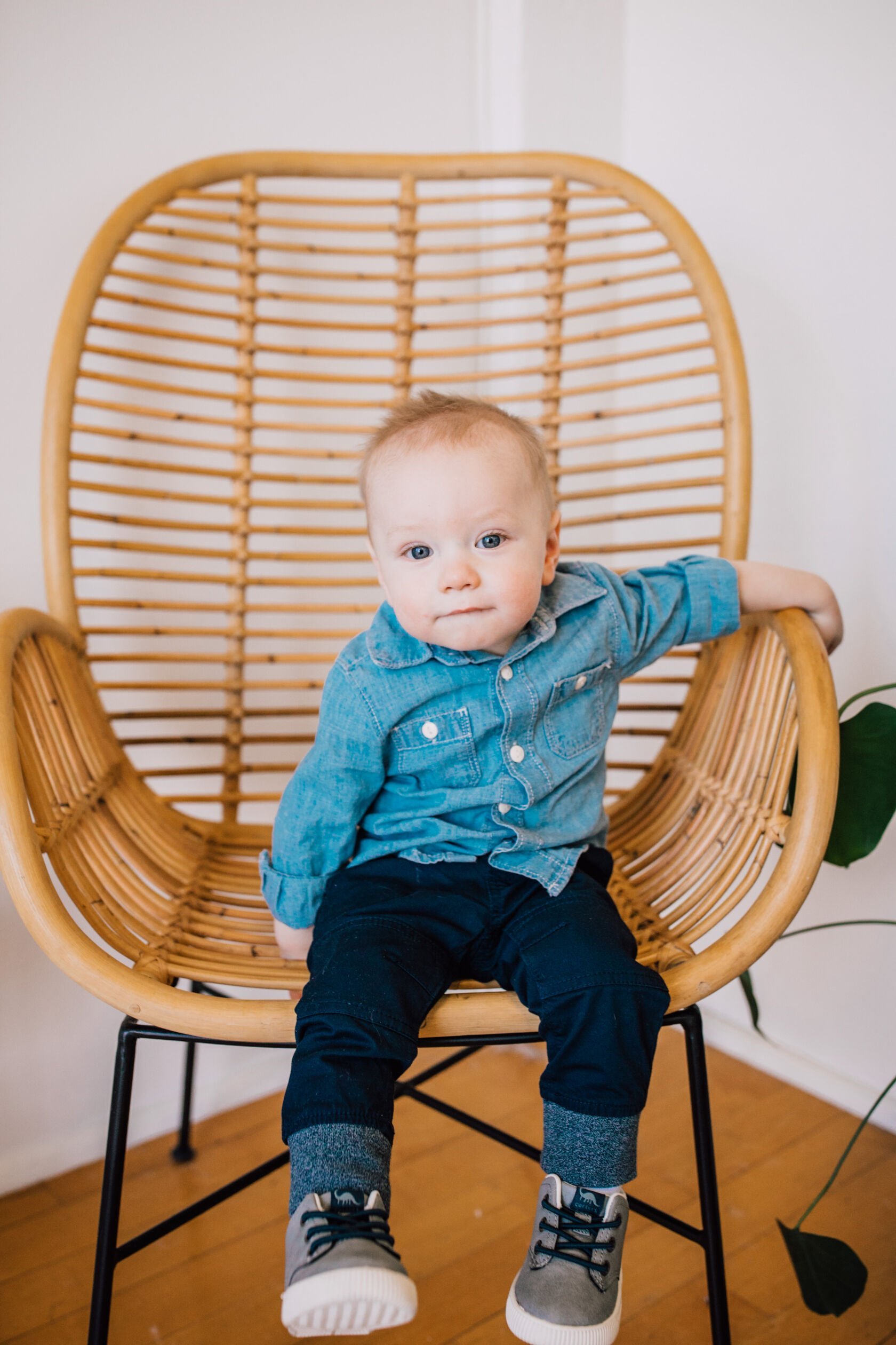  Little boy sits on a rattan chair during spring mini sessions 