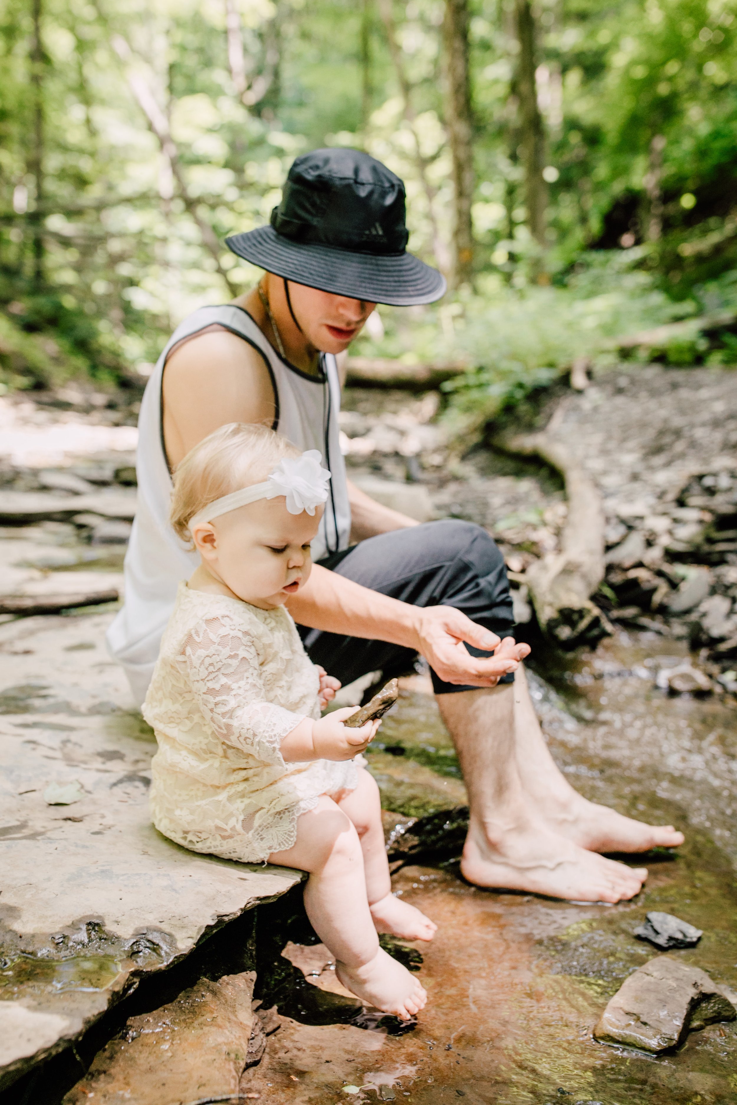  Dad and daughter play with rocks in a stream during their adventure photoshoot 