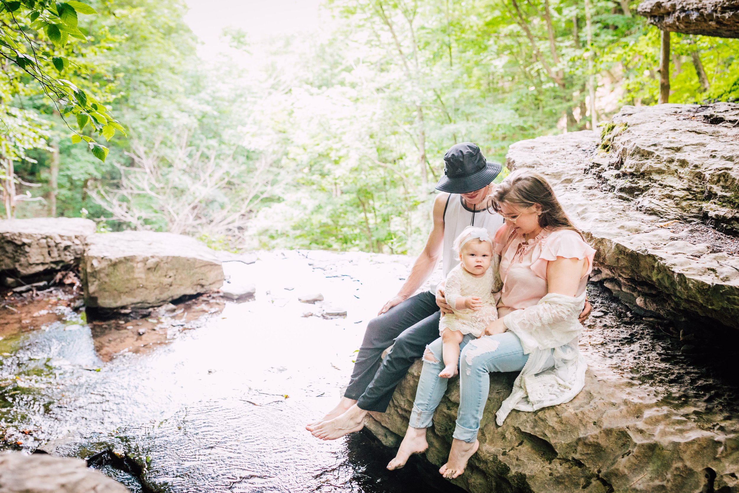  Syracuse family photographer captures family sitting together on a rock near a stream 