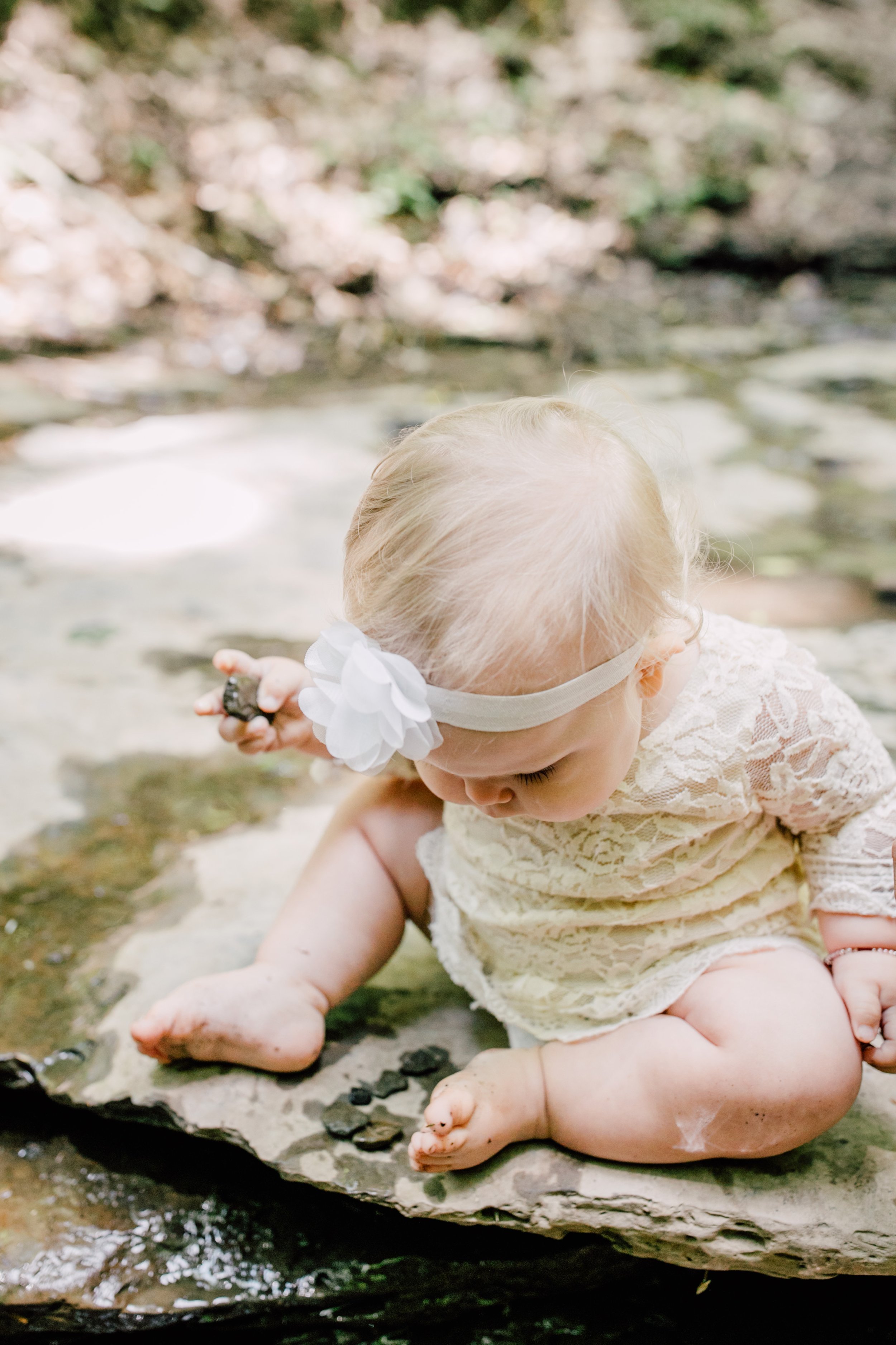  Baby girl sits on a rock and looks with curiosity during her family’s tinker falls photoshoot 