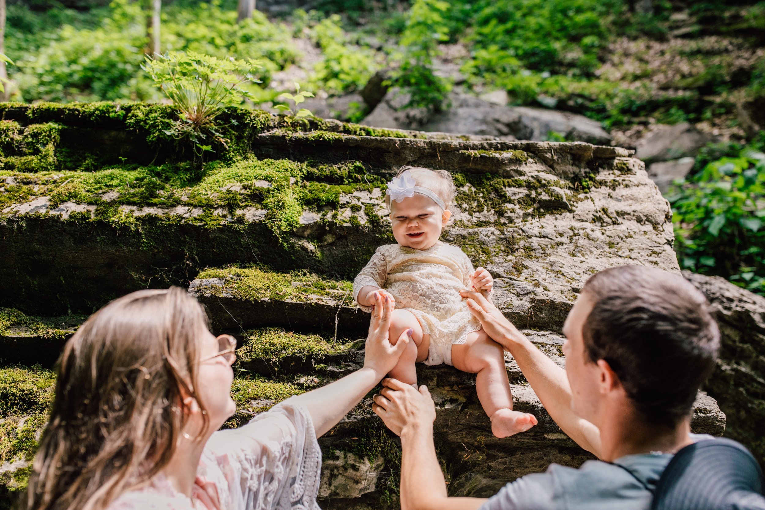  Parents hold their baby girl steady while she sits on a rock at tinker falls 