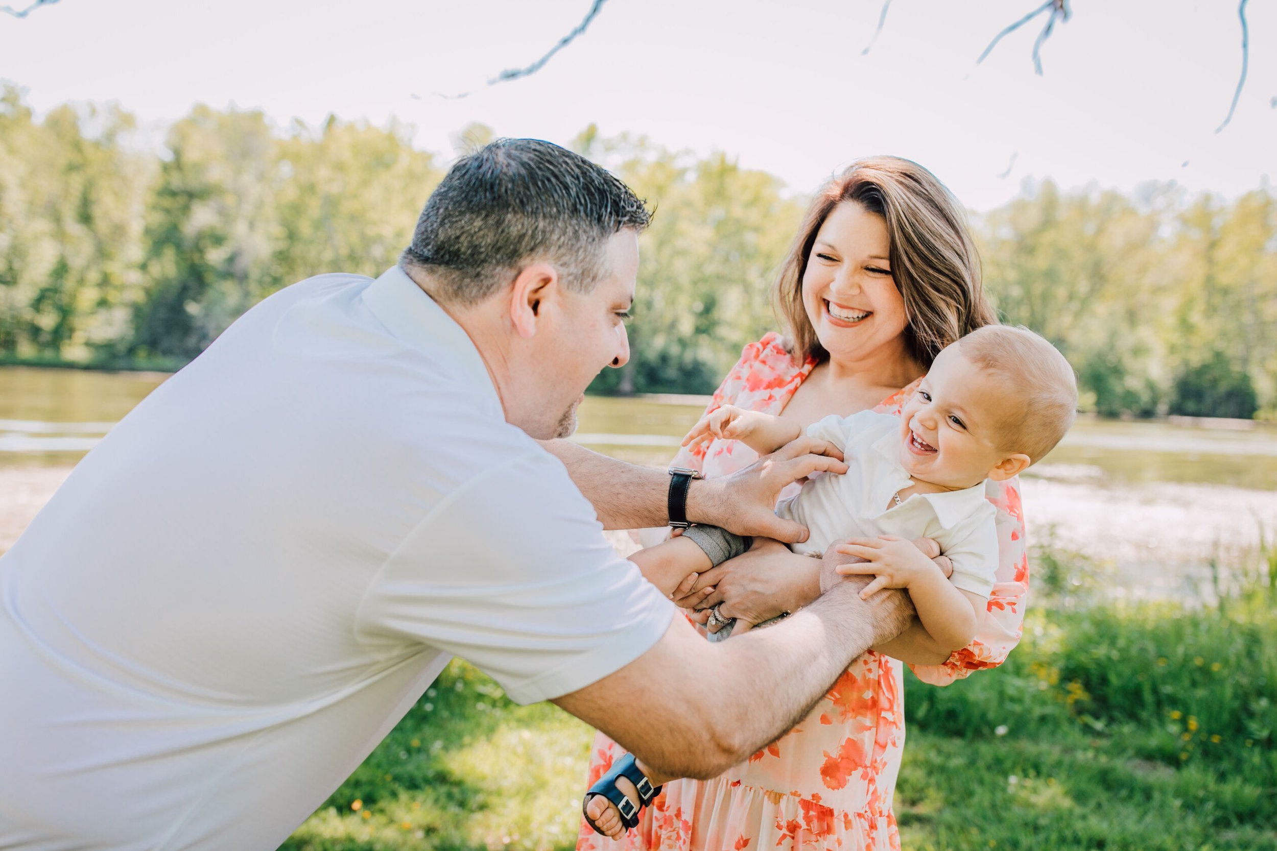  Family smiles as dad tickles their toddler in a family photo session 
