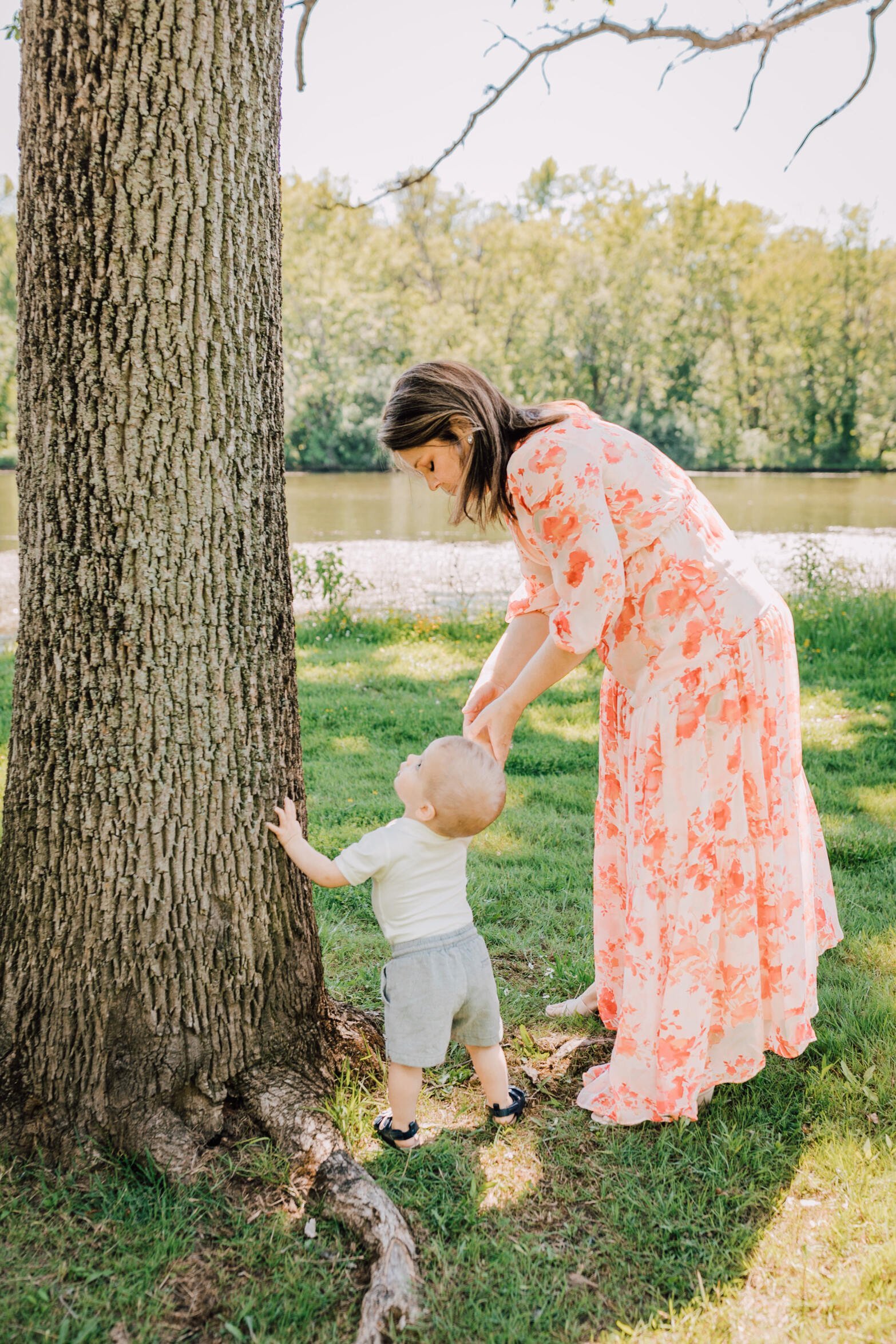  Mama holds hands with her toddler as he stares up at a tree at Onondaga Lake Parkway 