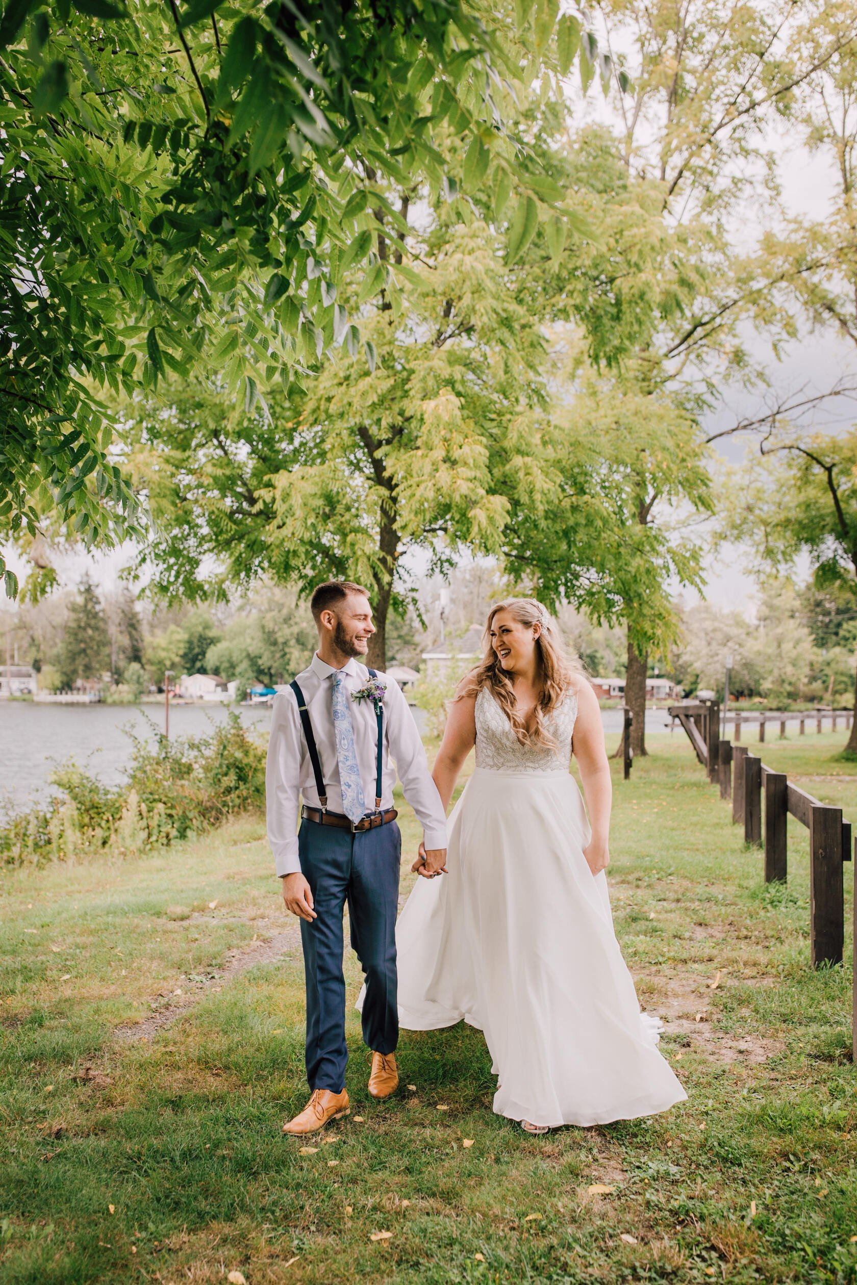  Bride and groom smile at each other while walking by a lake at 3 rivers park 