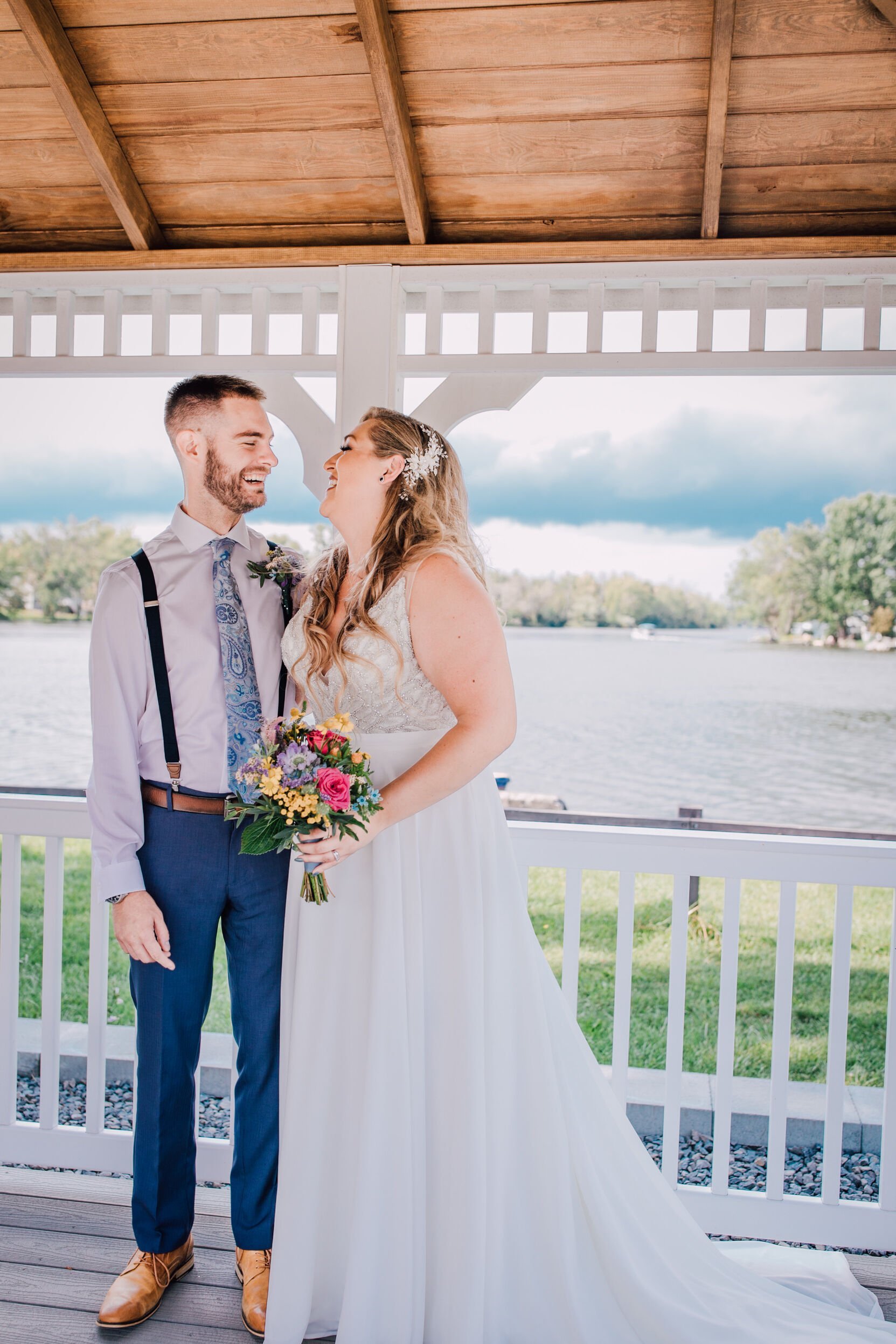  Bride and groom smile at each other on a gazebo over looking the water at 3 rivers park 