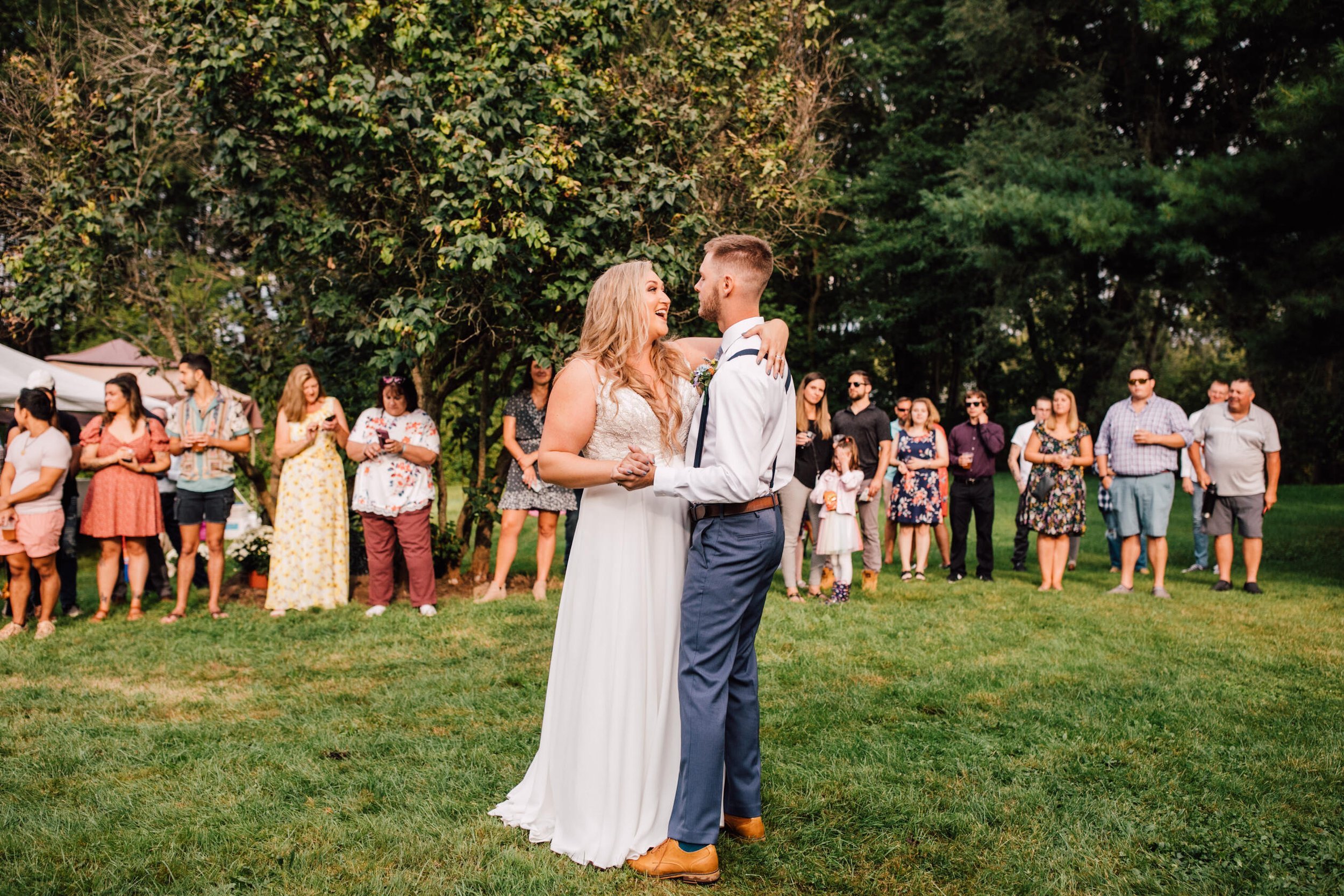  Bride and groom smile at each other during their first dance at their backyard wedding reception 