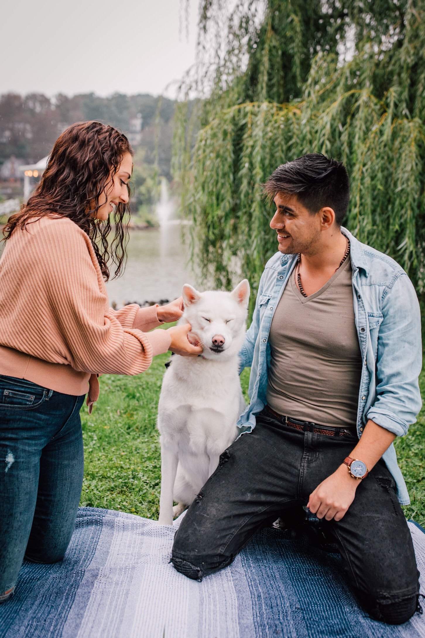  jessica pets their dog while pablo looks intently at her while they take engagement photos with a dog 