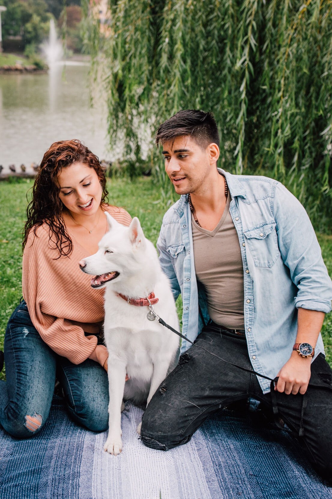  pablo looks at jessica adoringly as she looks at their dog who is smiling between them as they take dog engagement photos 