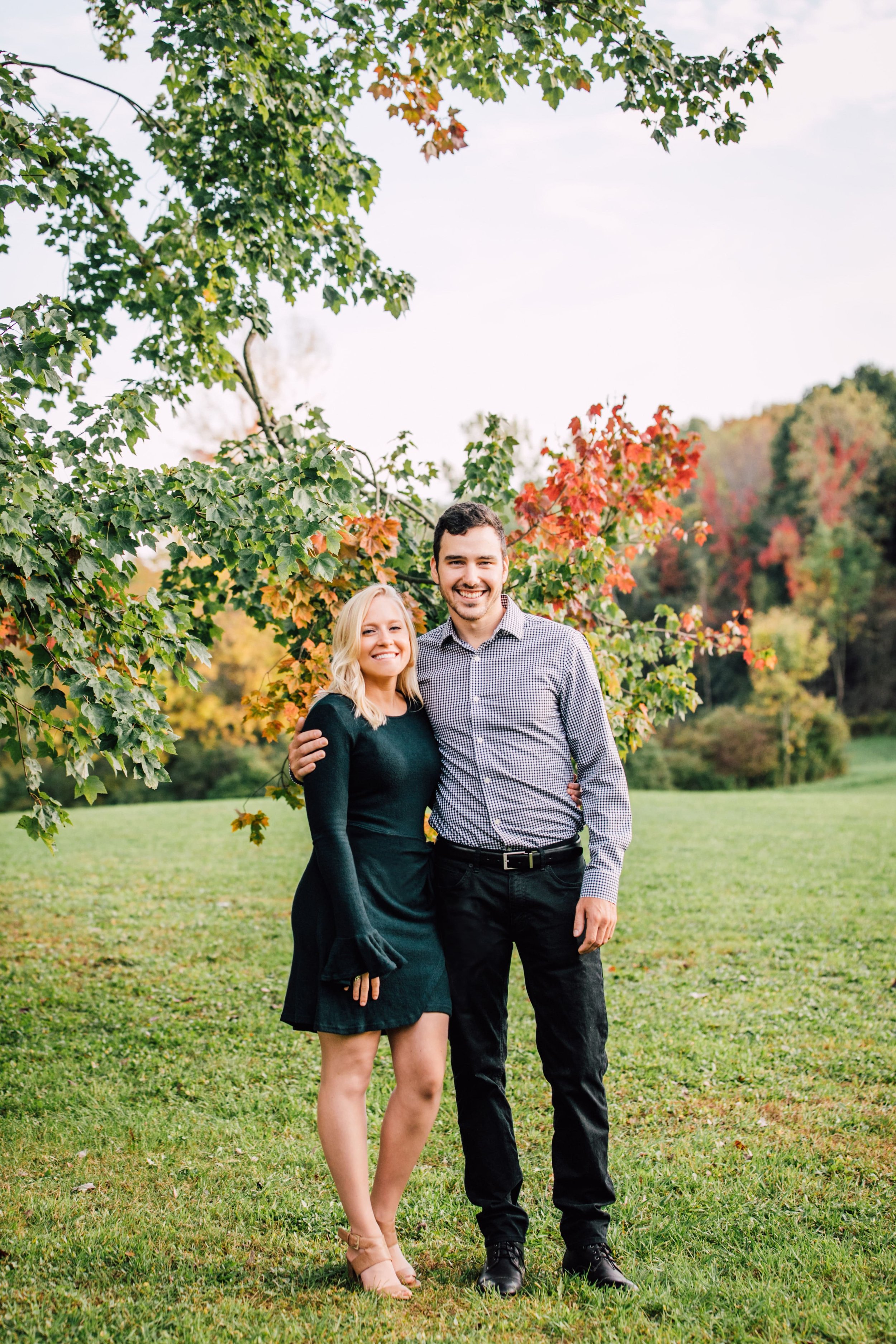  an engaged couple smile together at fallbrook lodge in oswego for fall pictures with their family 