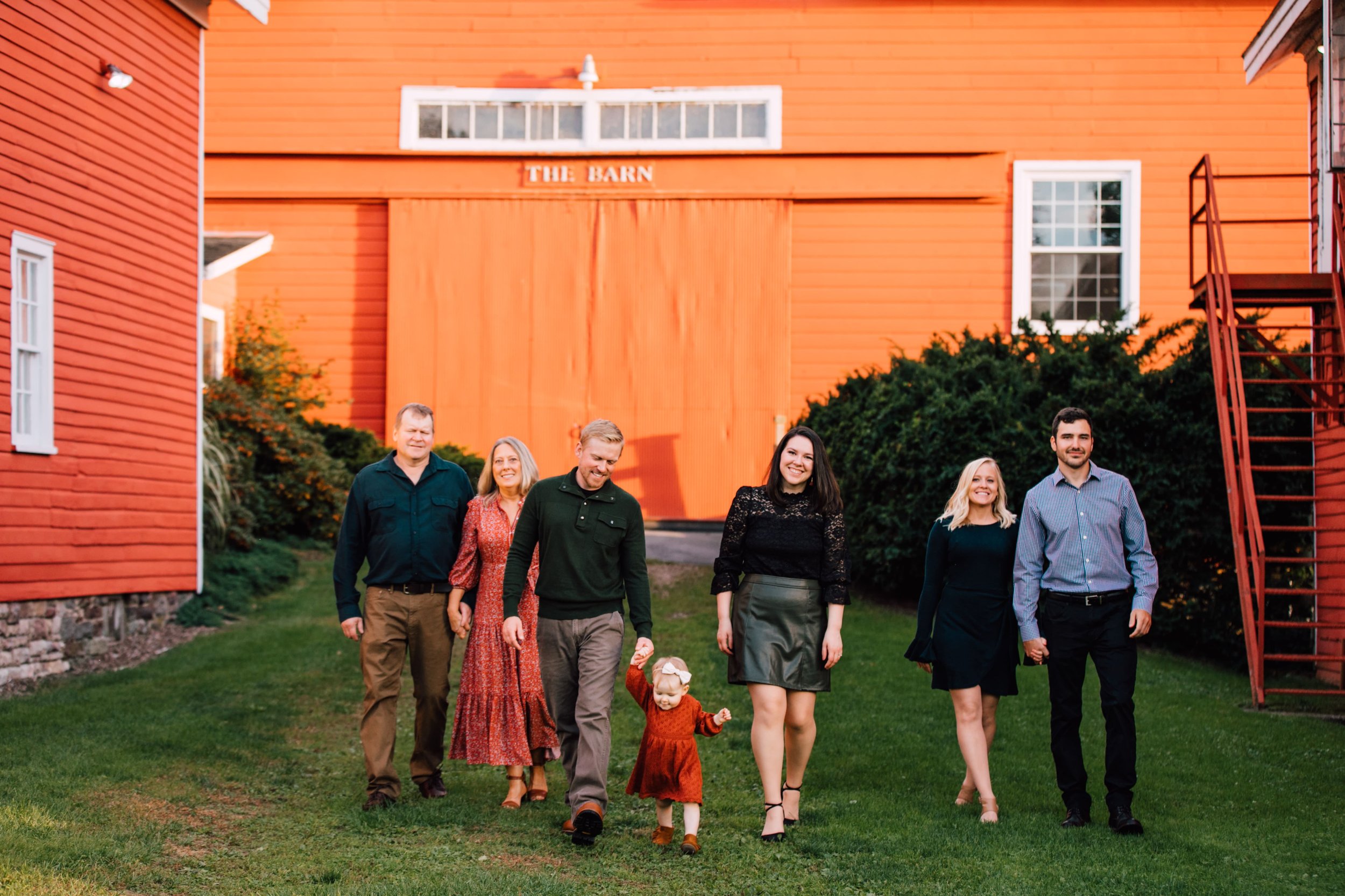  a family of 7 walk away from a red barn for adult family pictures 