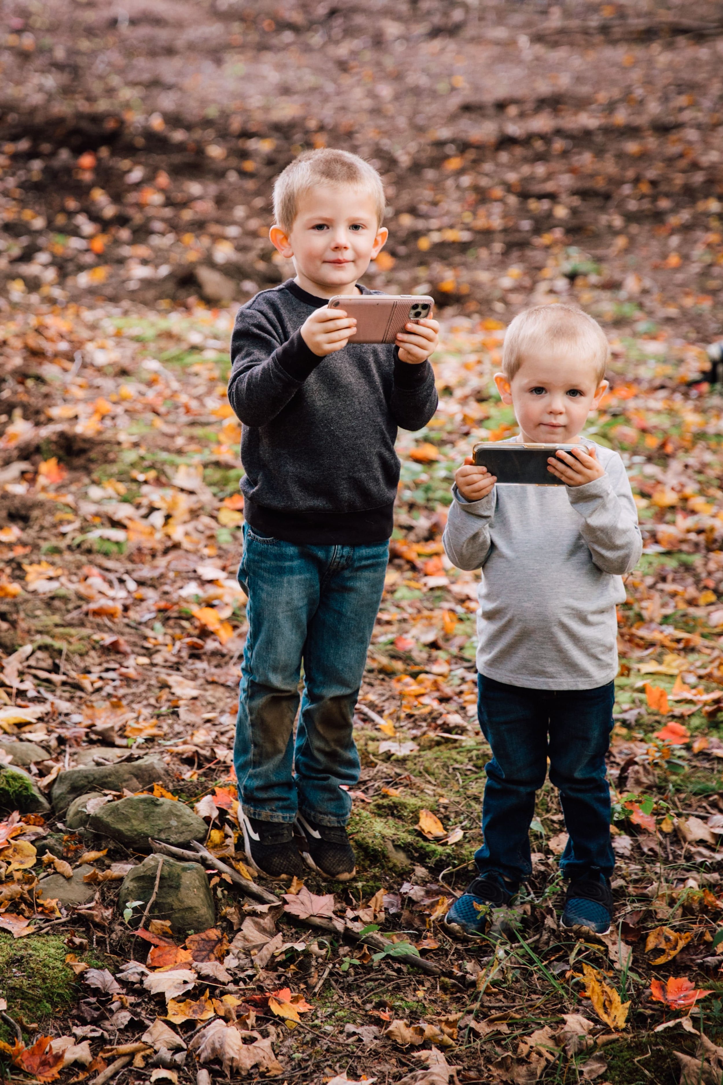  central new york photographer’s second shooters the couple’s sons stand with their parents phones taking pictures during their parents backyard photoshoot 