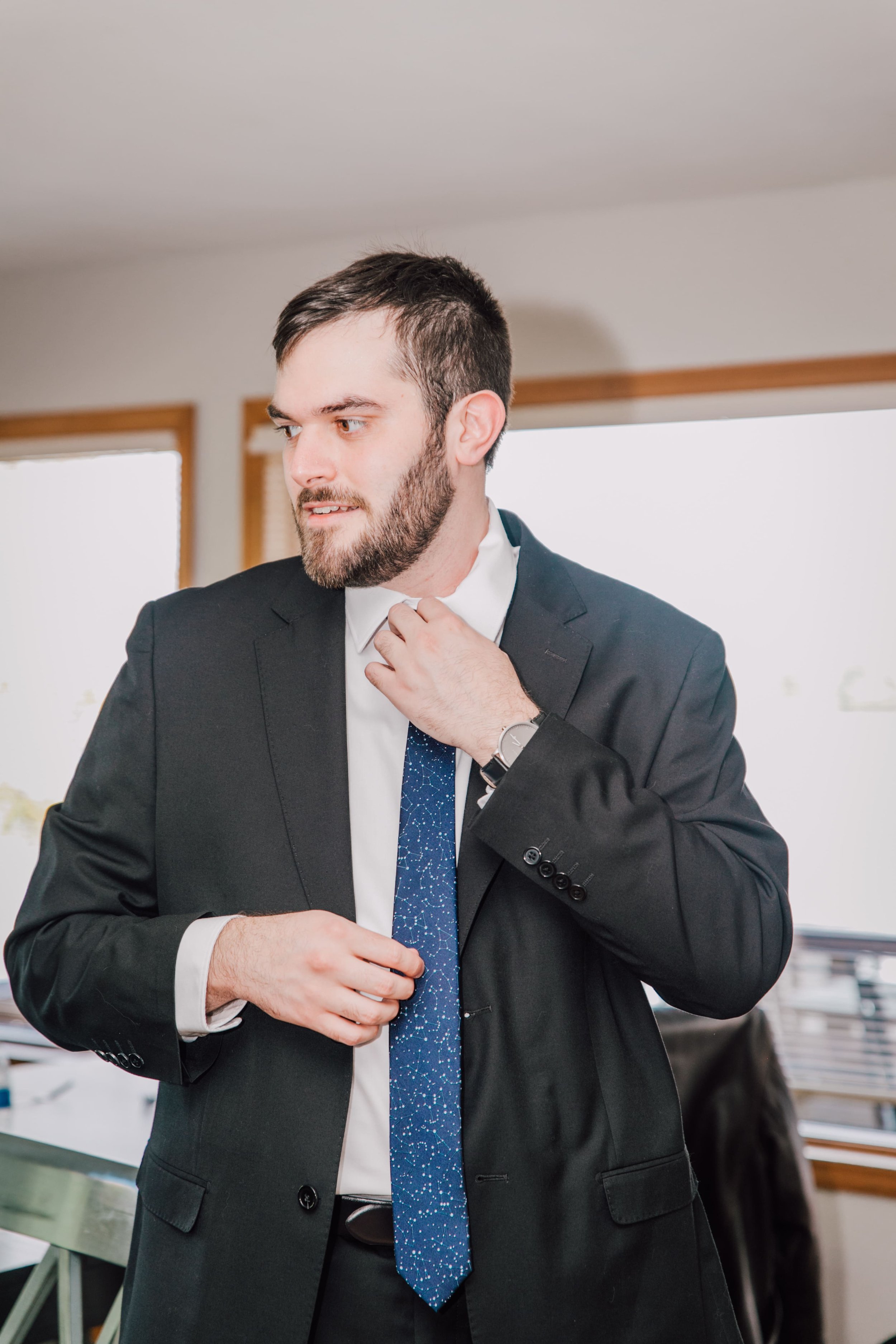  the groom straightens his tie as he is getting ready for his lake ontario wedding 