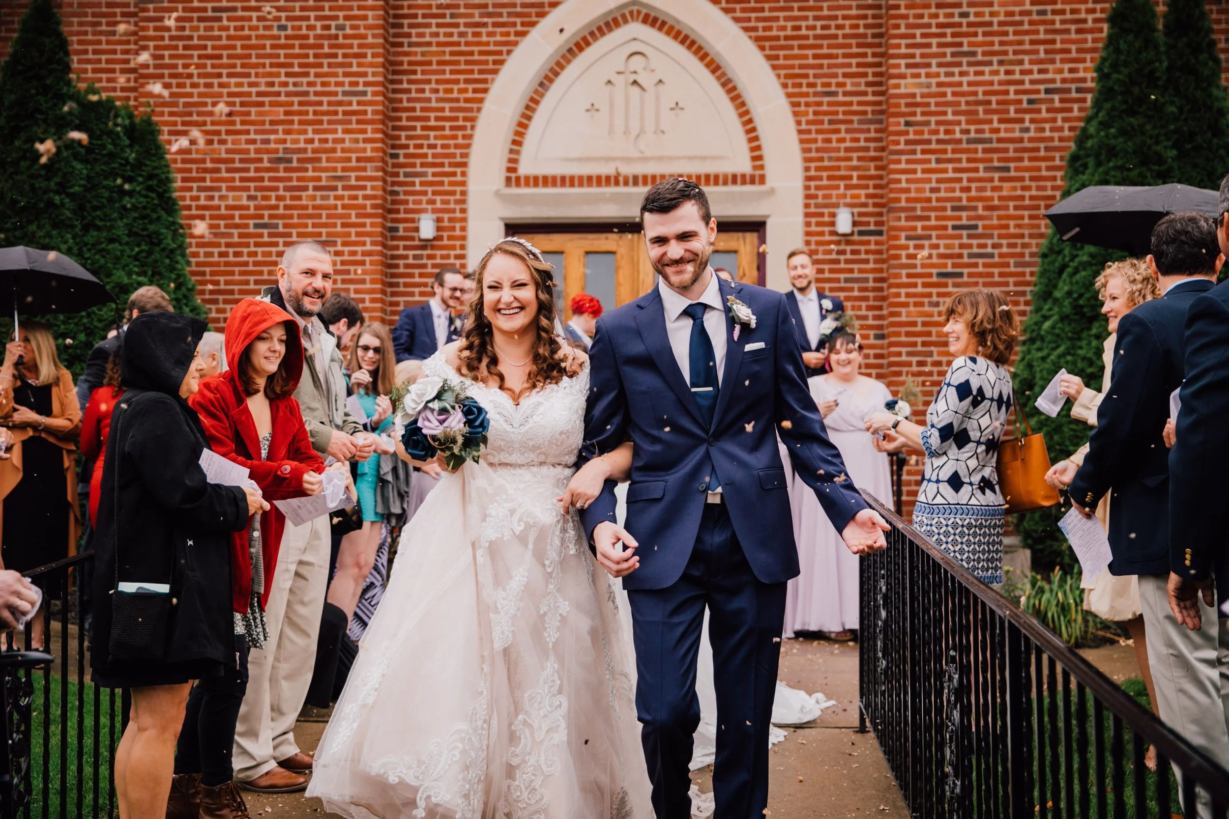  the bride and groom smile wide as they walk away from their wedding ceremony. the bride holds her bouquet of paper wedding flowers 