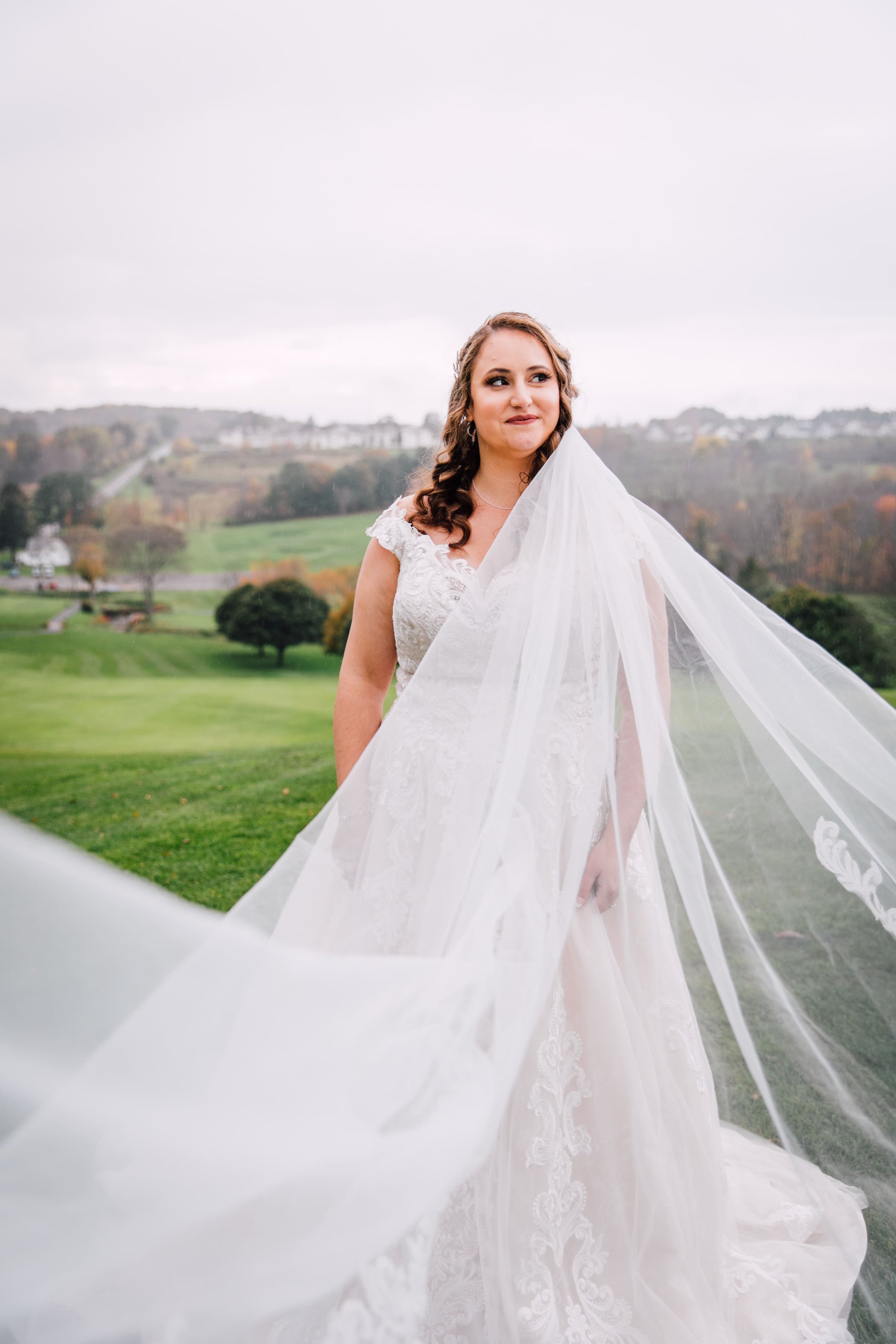  the bride looks to the right as her veil is stretched out in front of her at her fall wedding portraits 