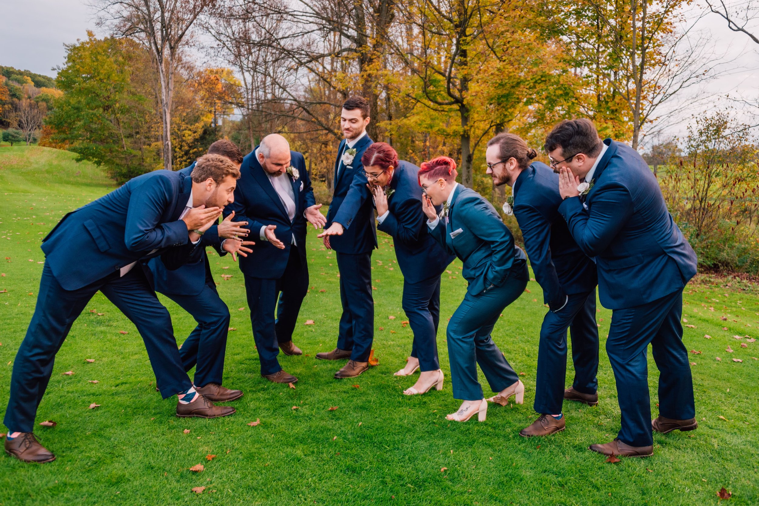  a wedding photographer captures the groom showing off his wedding ring as his groomsmen fawn over it at his fall wedding 