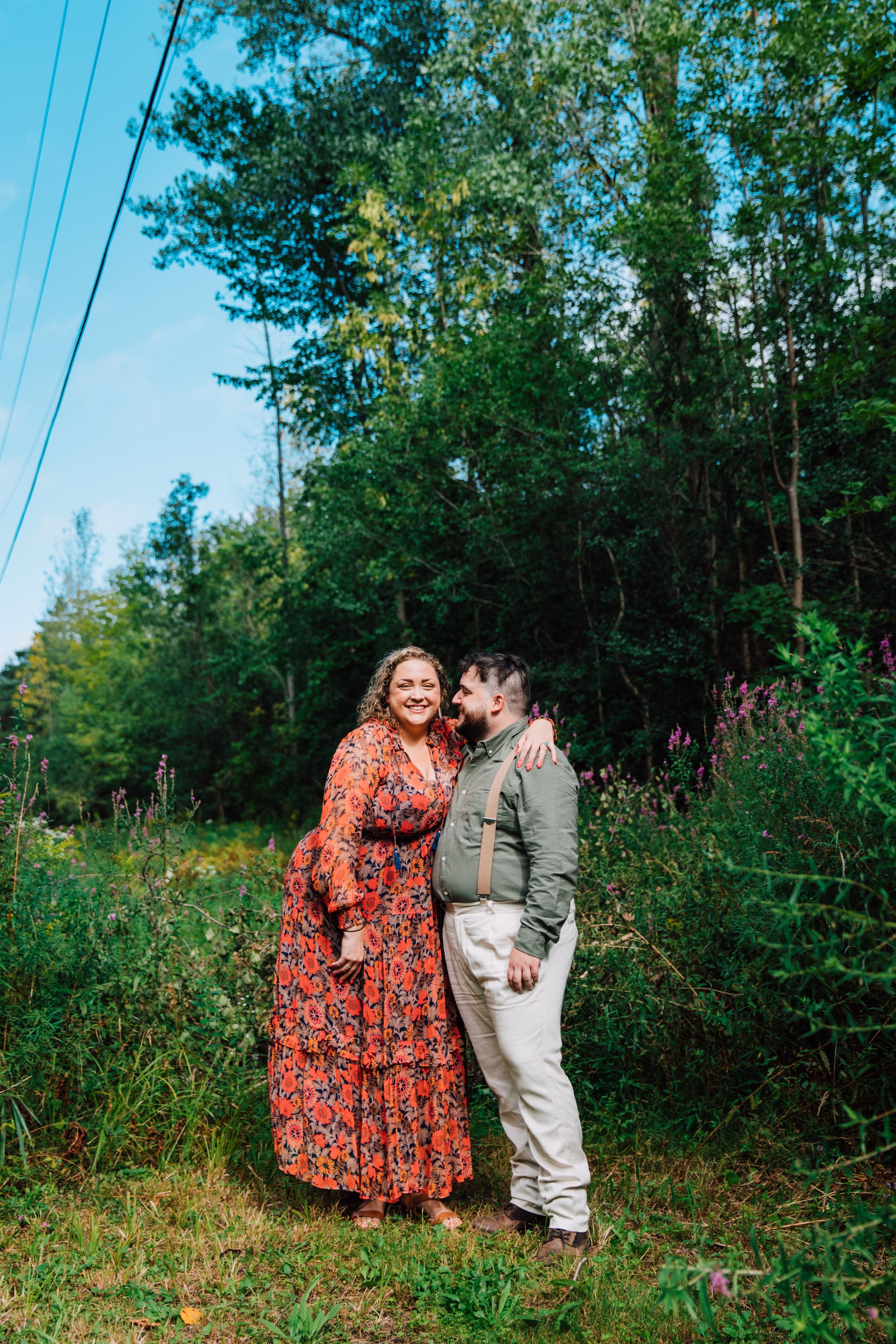  central new york photographer captured a photo of an engaged couple standing in front of wildflowers in front of a forest at rice creek field station 
