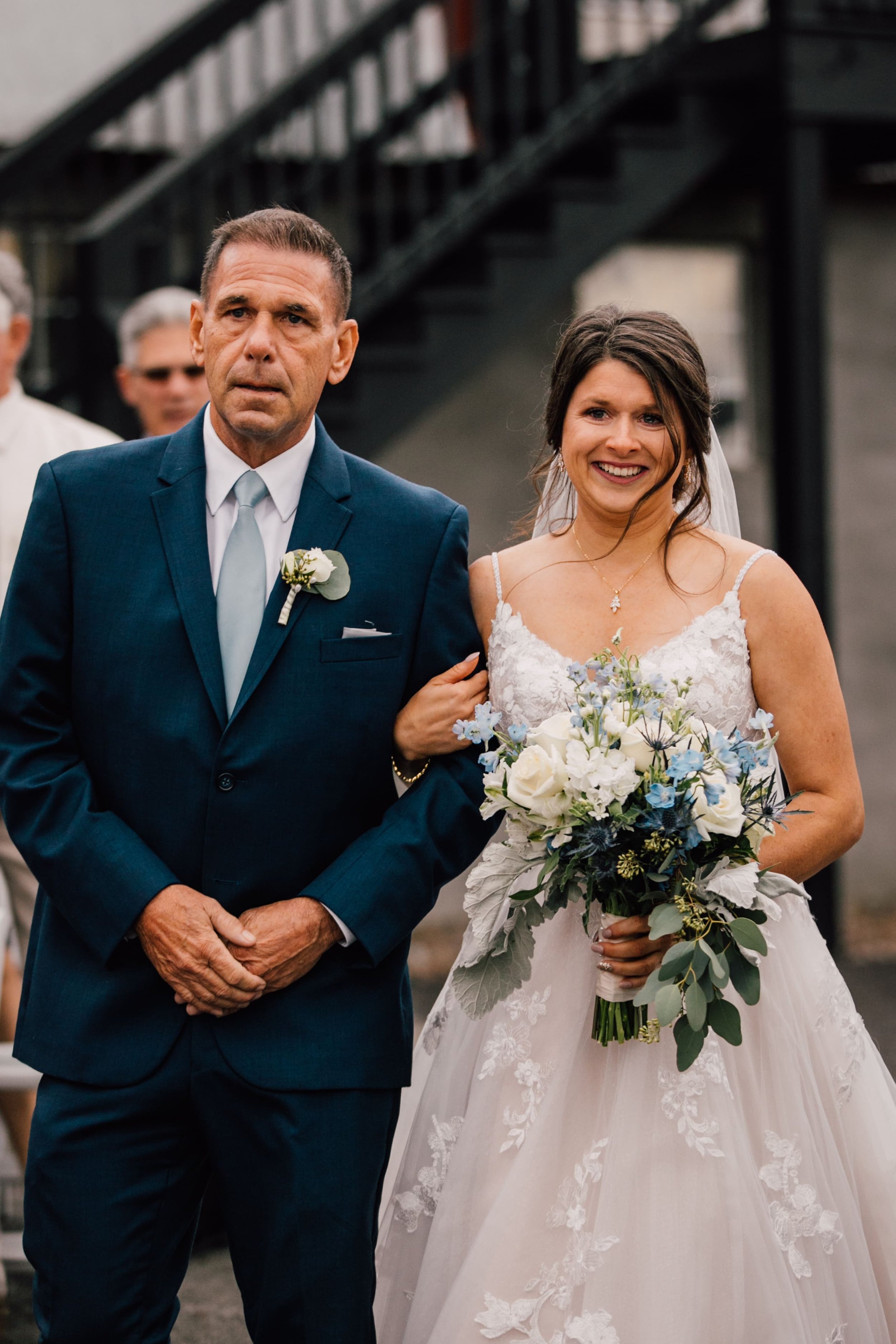  the bride smiles as she walks down the aisle with her father at her outdoor fall wedding 