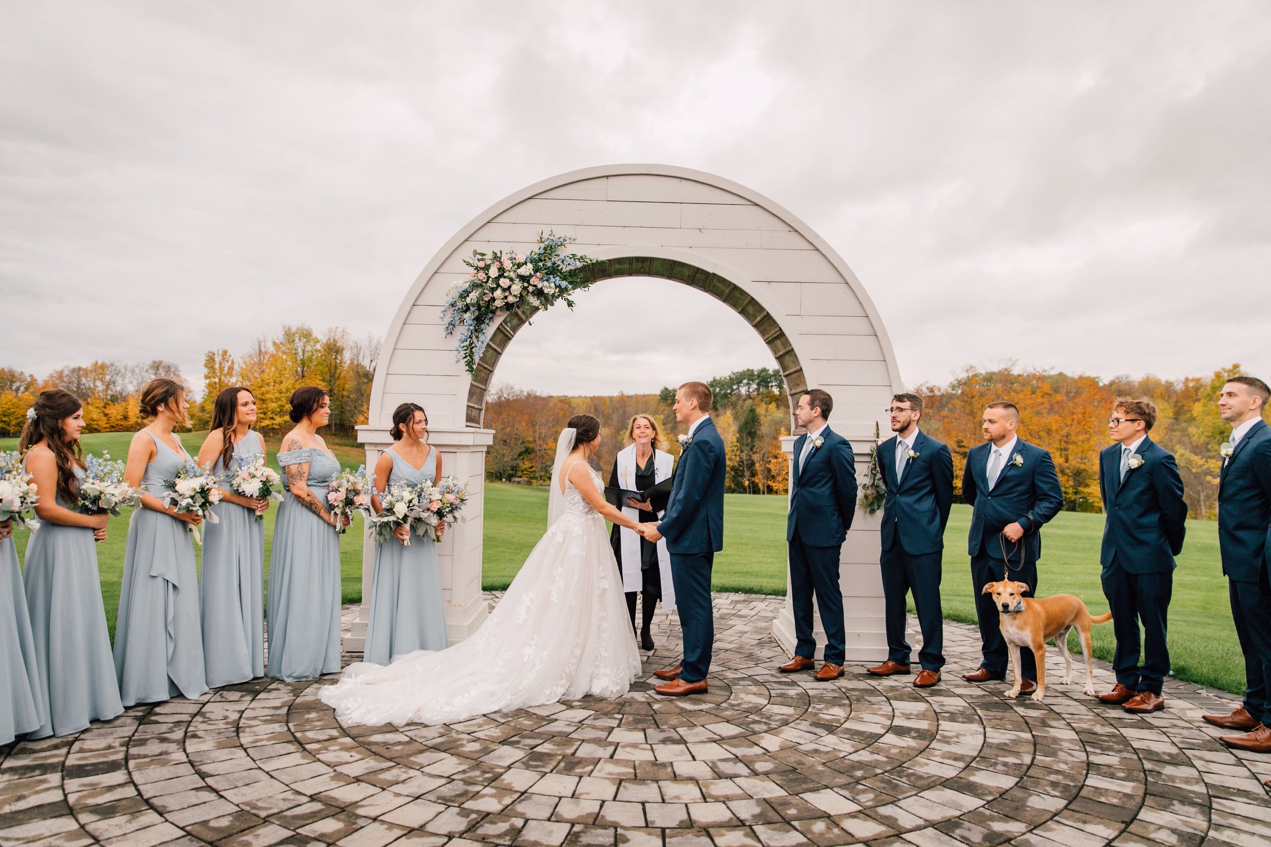  the bride and groom stand together during their outdoor fall wedding ceremony at hayloft on the arch  