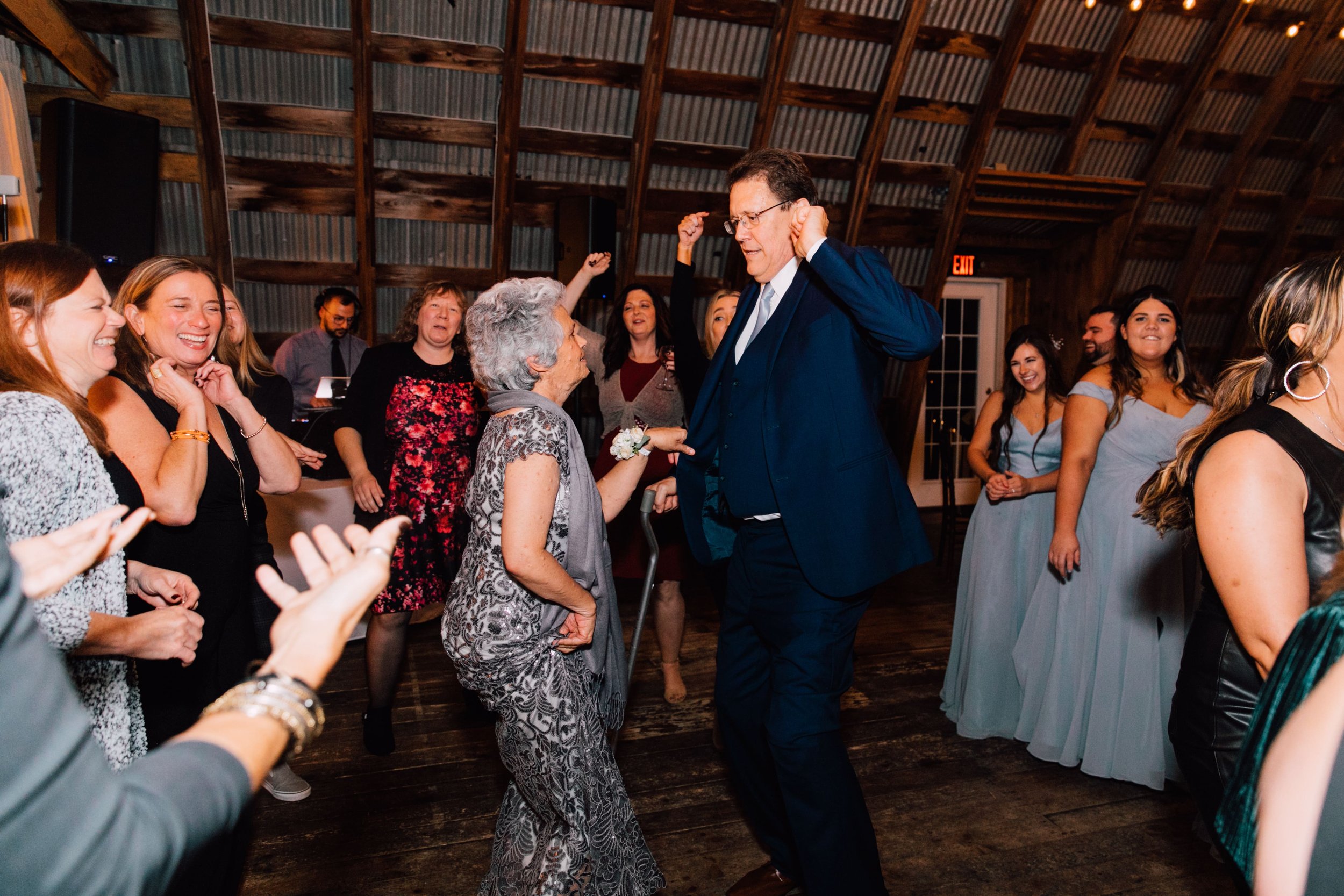  wedding guests and parents of the groom dance at an elegant barn wedding 