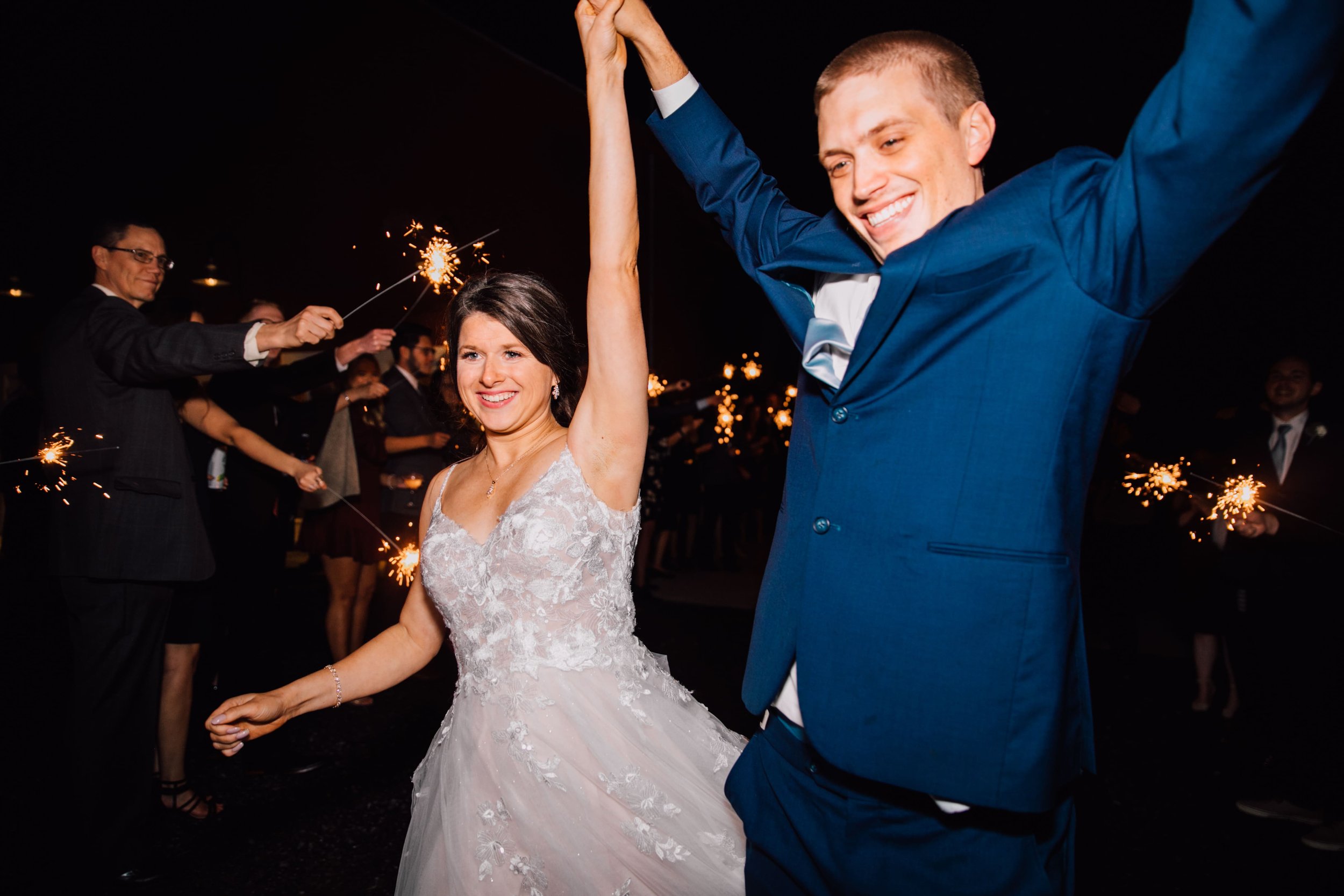  the bride and groom celebrate with their arms in the air during the sparkler exit at their rustic fall wedding 