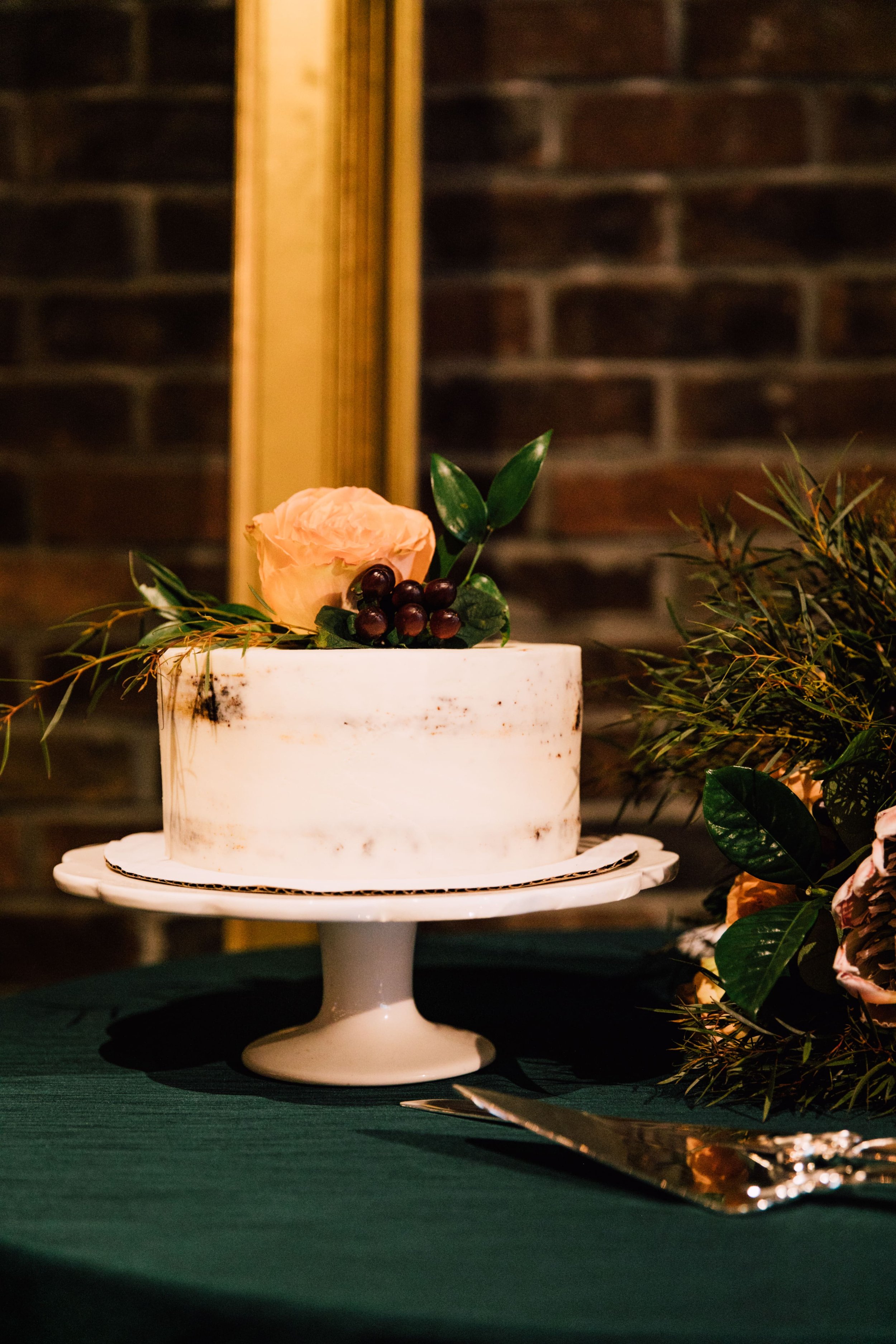  syracuse ny photographer captured a photo of a simple wedding cake from a fall wedding. it is a simple naked cake with flowers and berries resting on top 