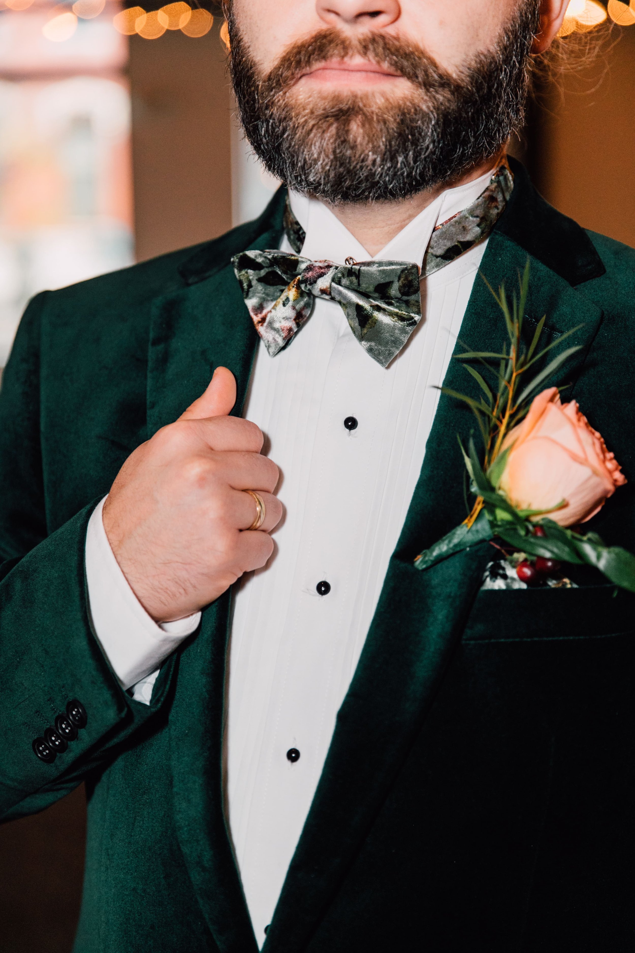  an upclose shot of the groom’s details. he rests his hand on his green velvet jacket while syracuse wedding photographer captures the details of his outfit and boutonniere  