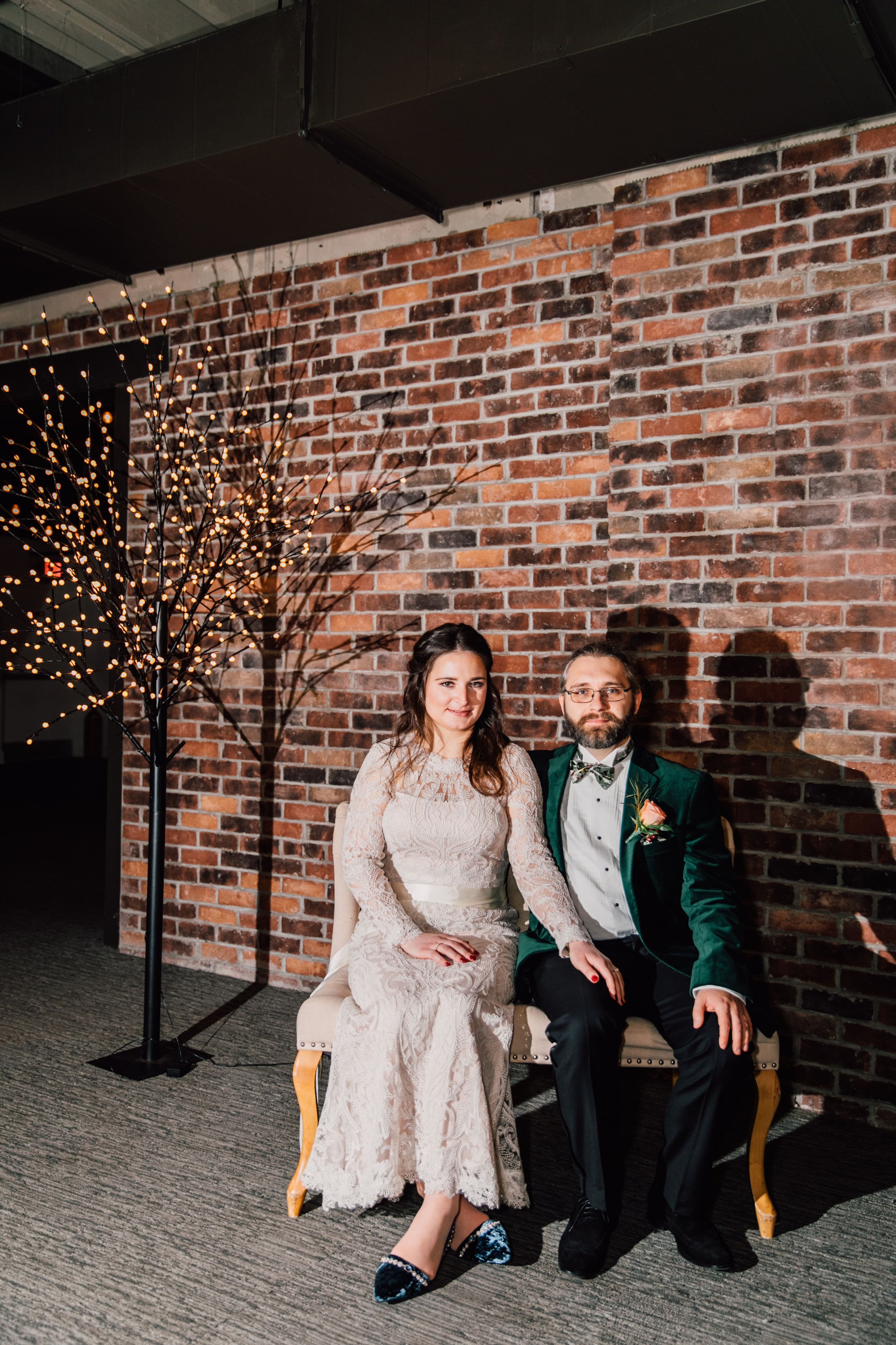  the bride and groom sit on a bench and smile at their sky armory wedding 