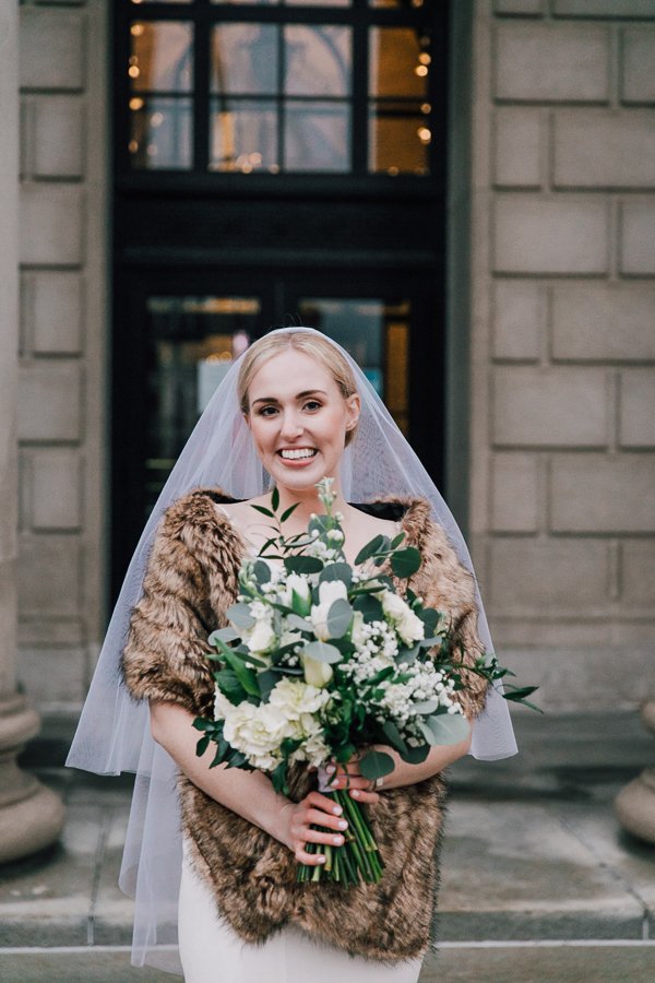  Bride smiles at the camera during winter elopement portraits in downtown Syracuse 