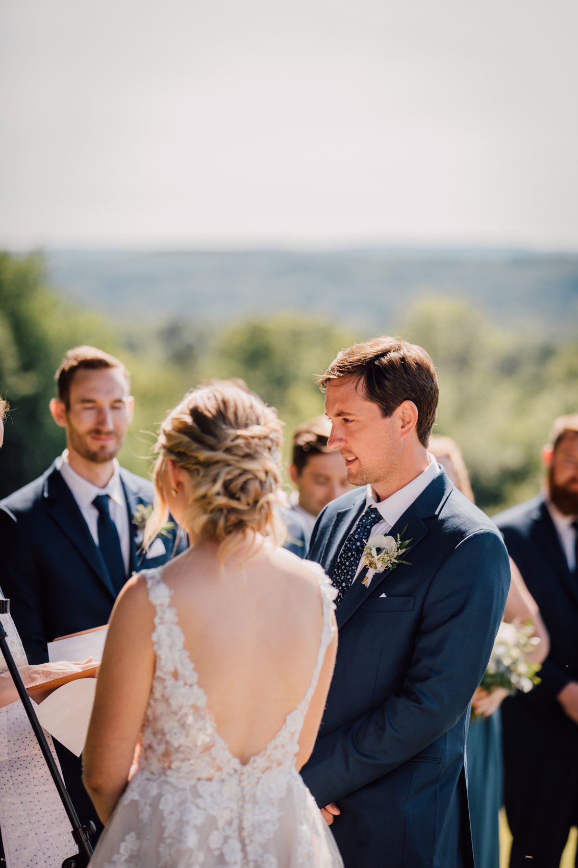  Groom listens to the officiant during an outdoor barn wedding in Central NY 