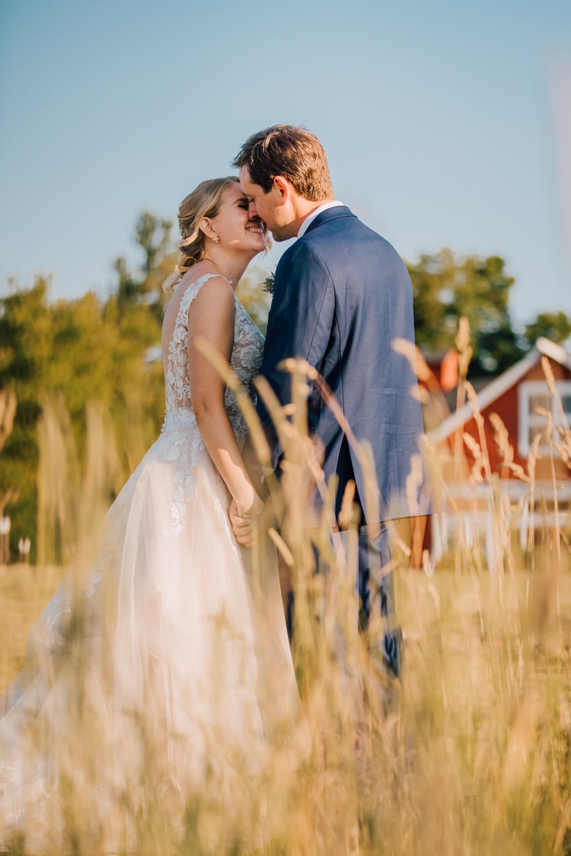  Bride and Groom stand in a field of tall grass at sunset taking wedding photos with Brittany Juravich 