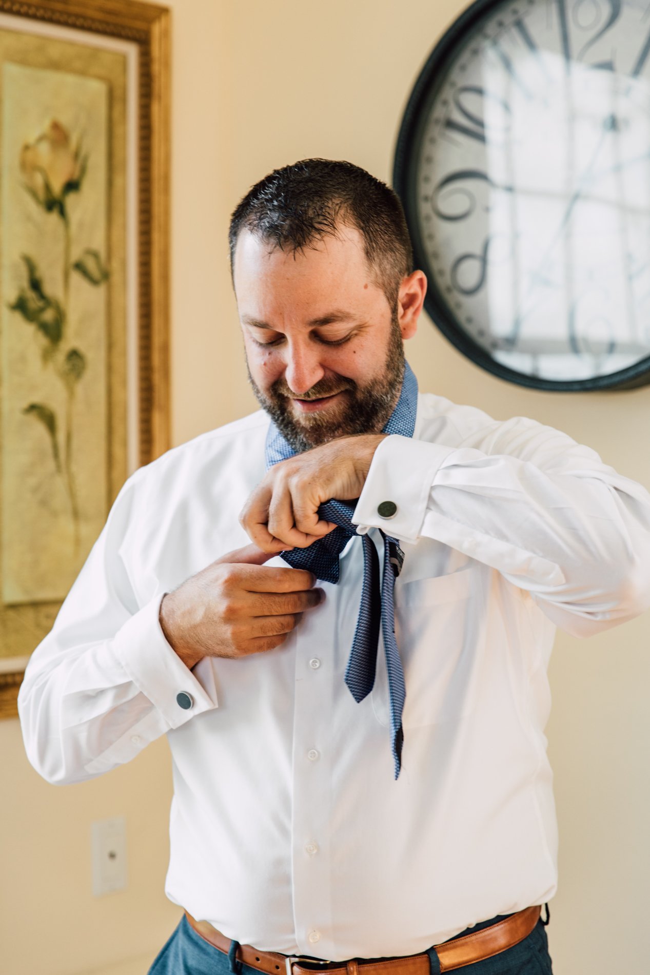  Groom puts on his tie while preparing for his modern wedding at Taughannock Falls 
