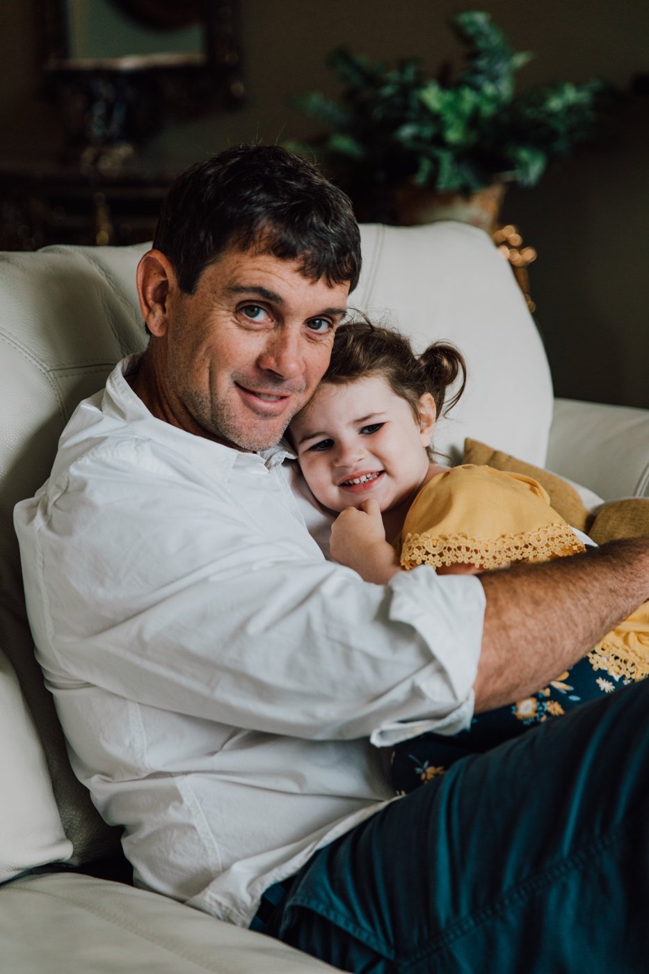  Father and daughter cuddle on the couch during lifestyle family photos in Syracuse NY 