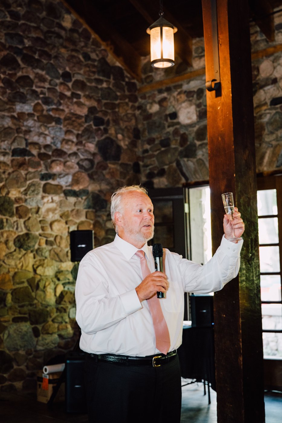  Man holds up a glass of champagne while giving a wedding reception toast 