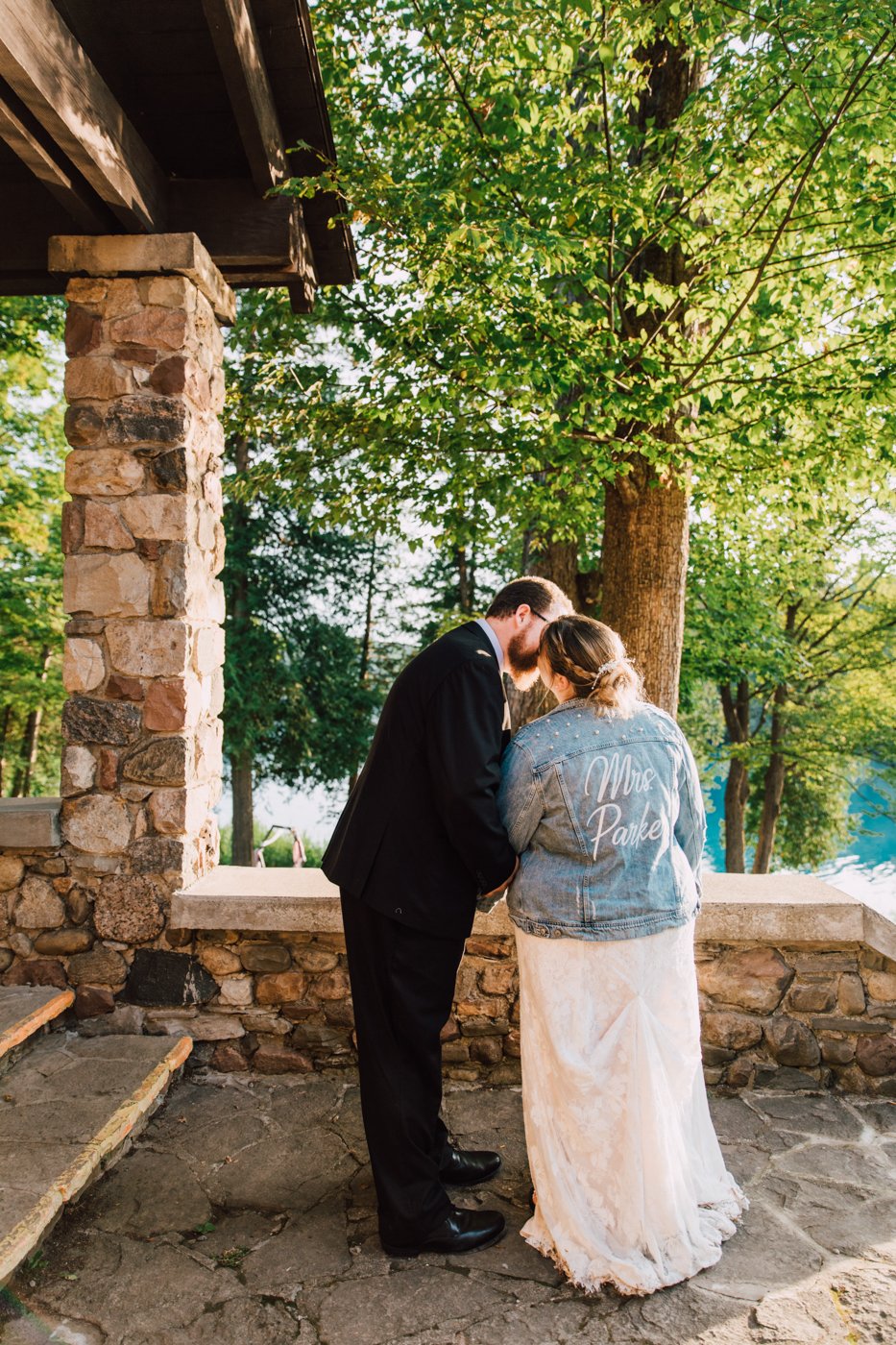  Bride wearing a custom bride jean jacket kisses her new husband 