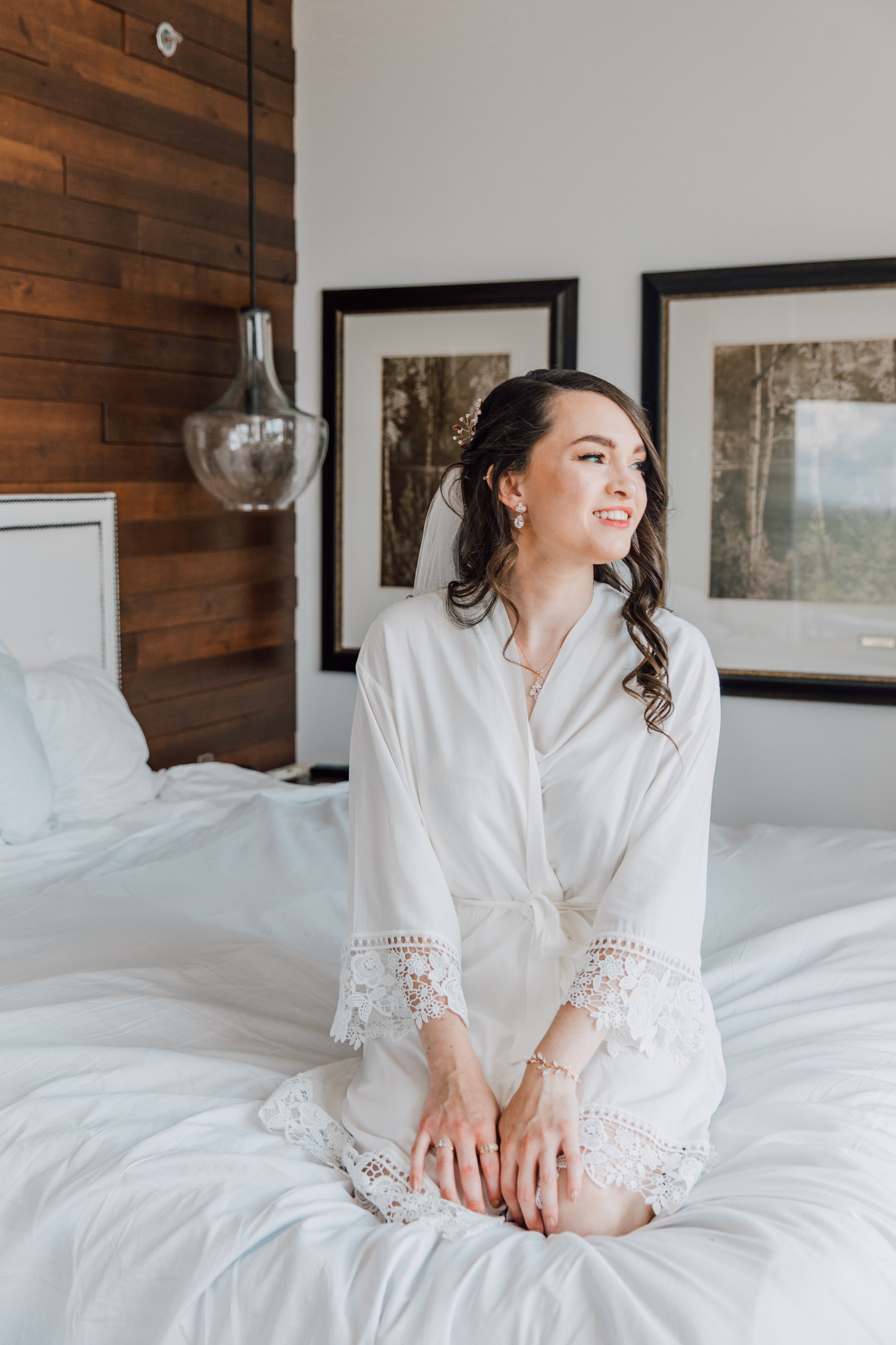  Bride poses on the bed in a white robe at The Tower at Turning Stone 