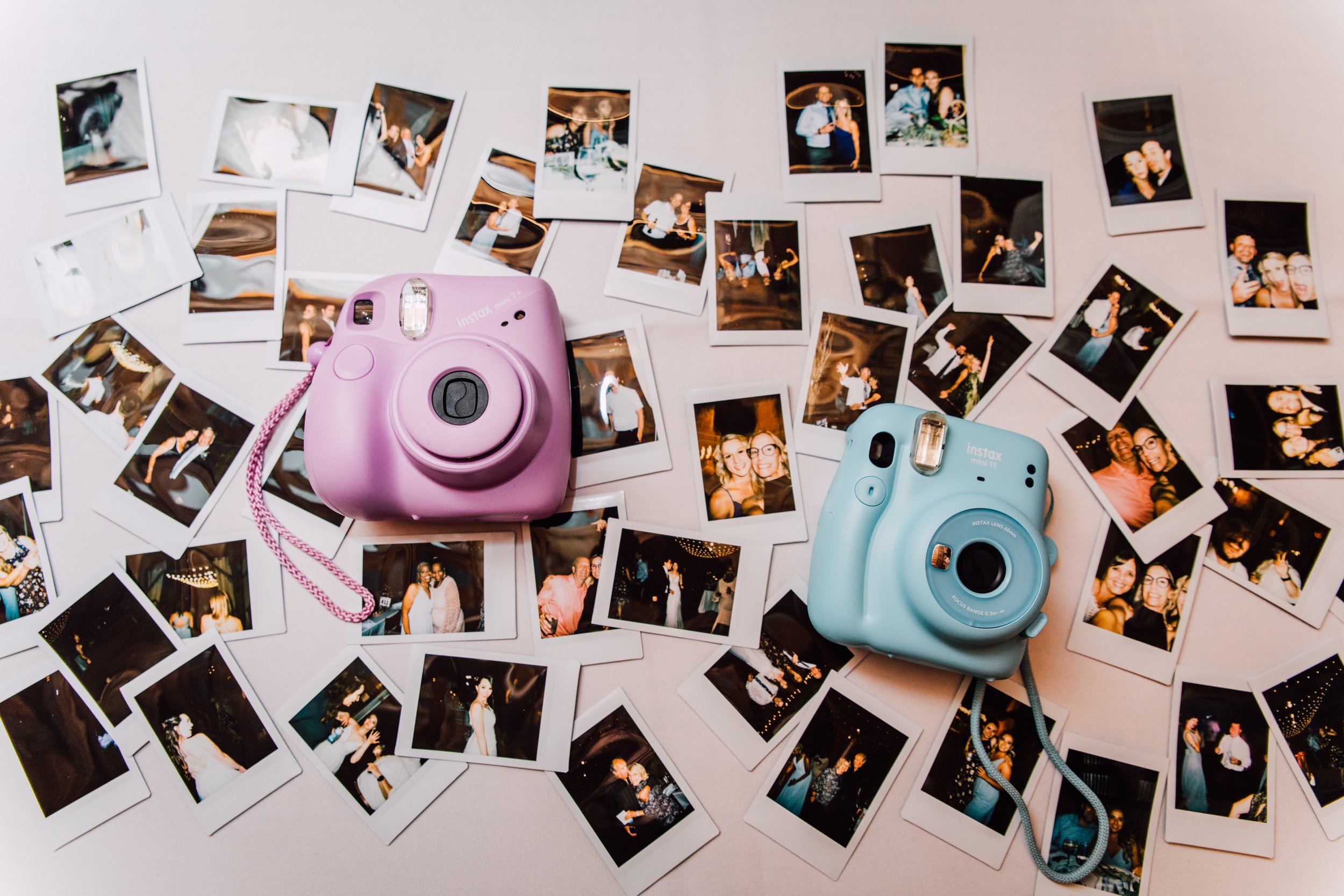  Polaroid cameras lay on top of a pile of photos at a wedding reception 