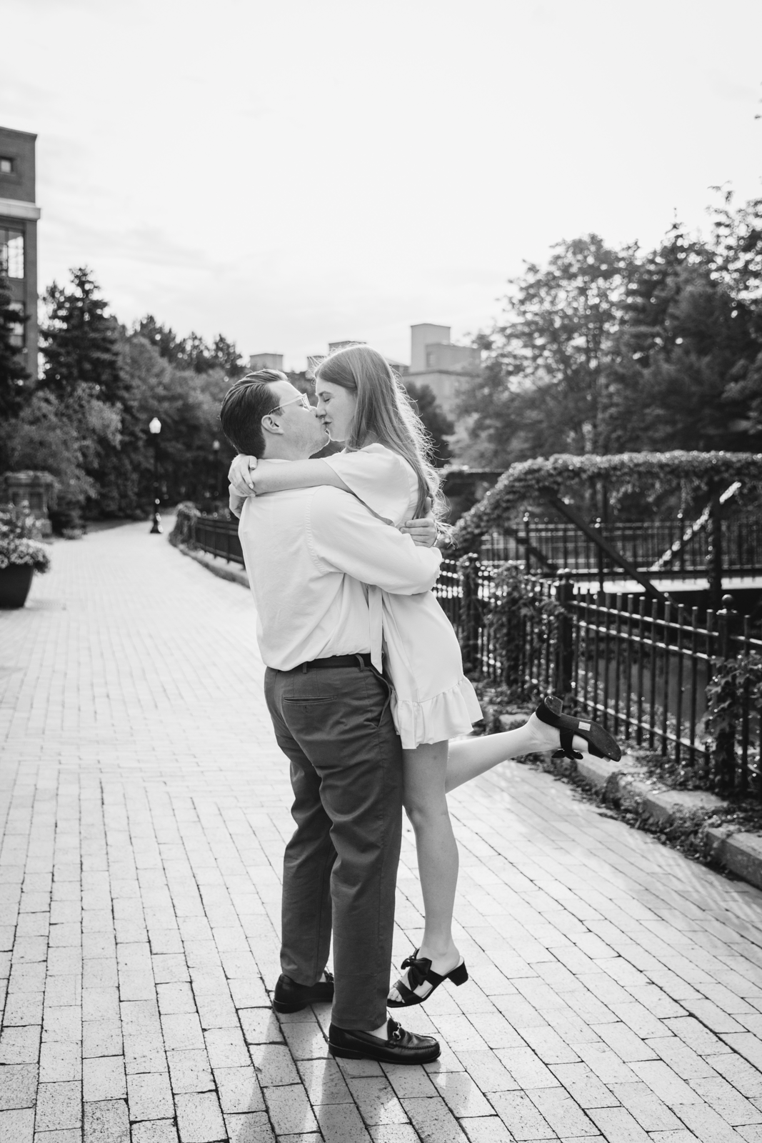  Man lifts woman up in the air while kissing her during timeless engagement photos in downtown syracuse 