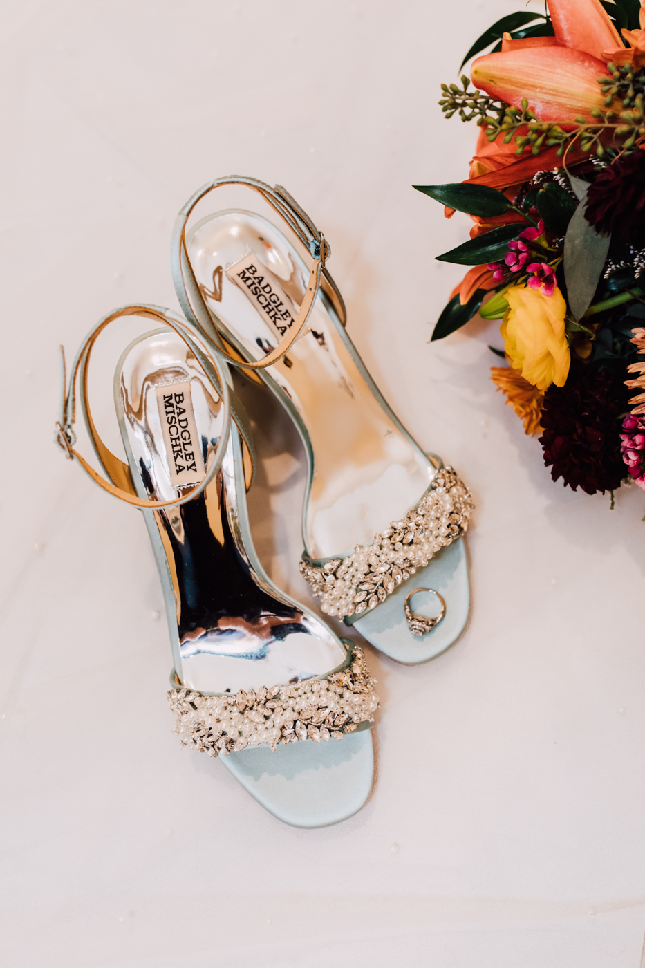  Bride’s shoes with engagement ring and fall flowers in her bouquet 