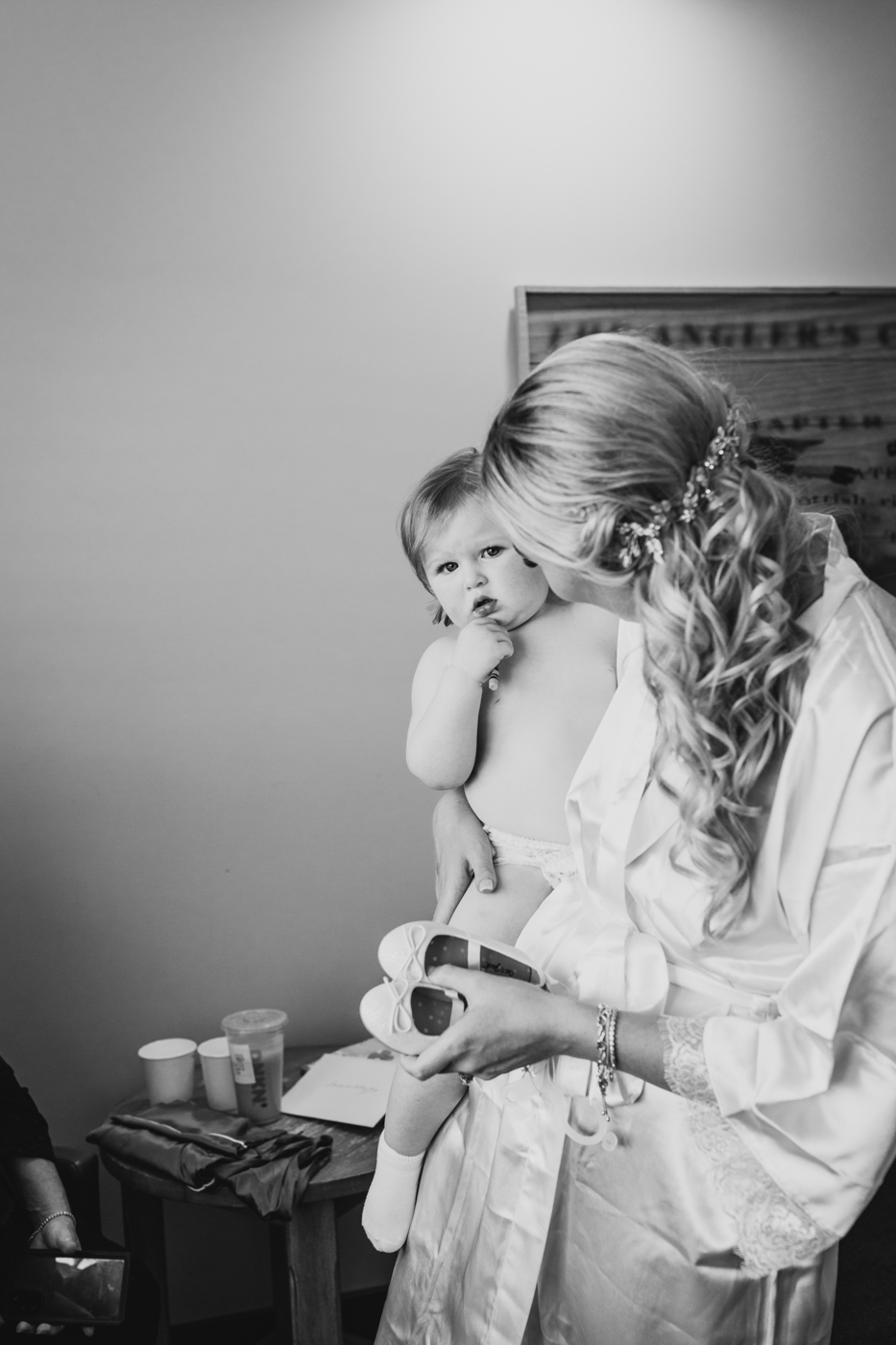  Bride holds her toddler while getting ready for her fall wedding at Tailwater Lodge 