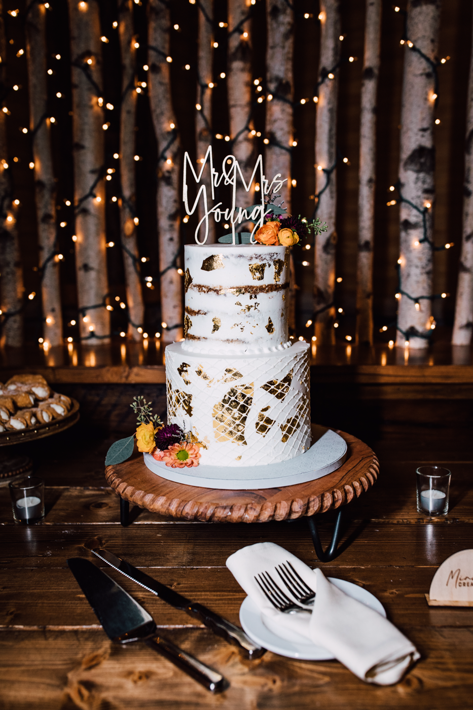  Rustic fall wedding cake on a wooden table with string lights behind it at a Tailwater Lodge wedding reception 