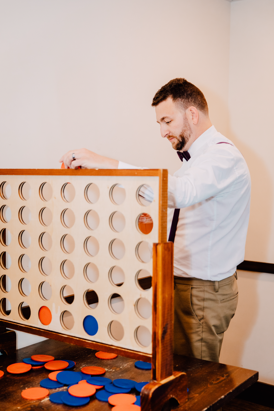  Groomsman playing connect four on a large set before the wedding 