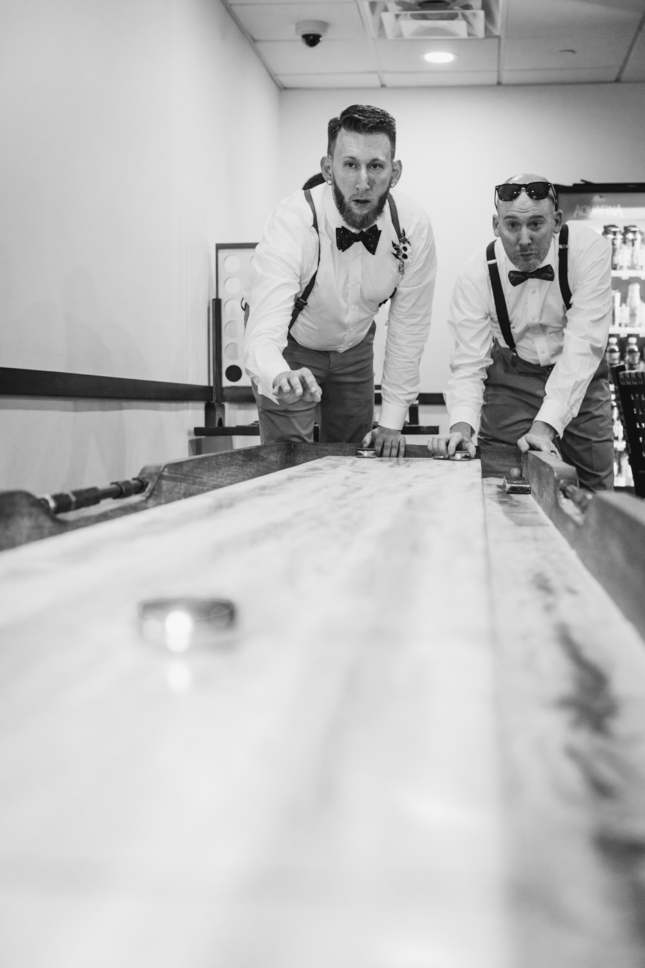  Groom and Groomsman play tabletop shuffleboard before the wedding 