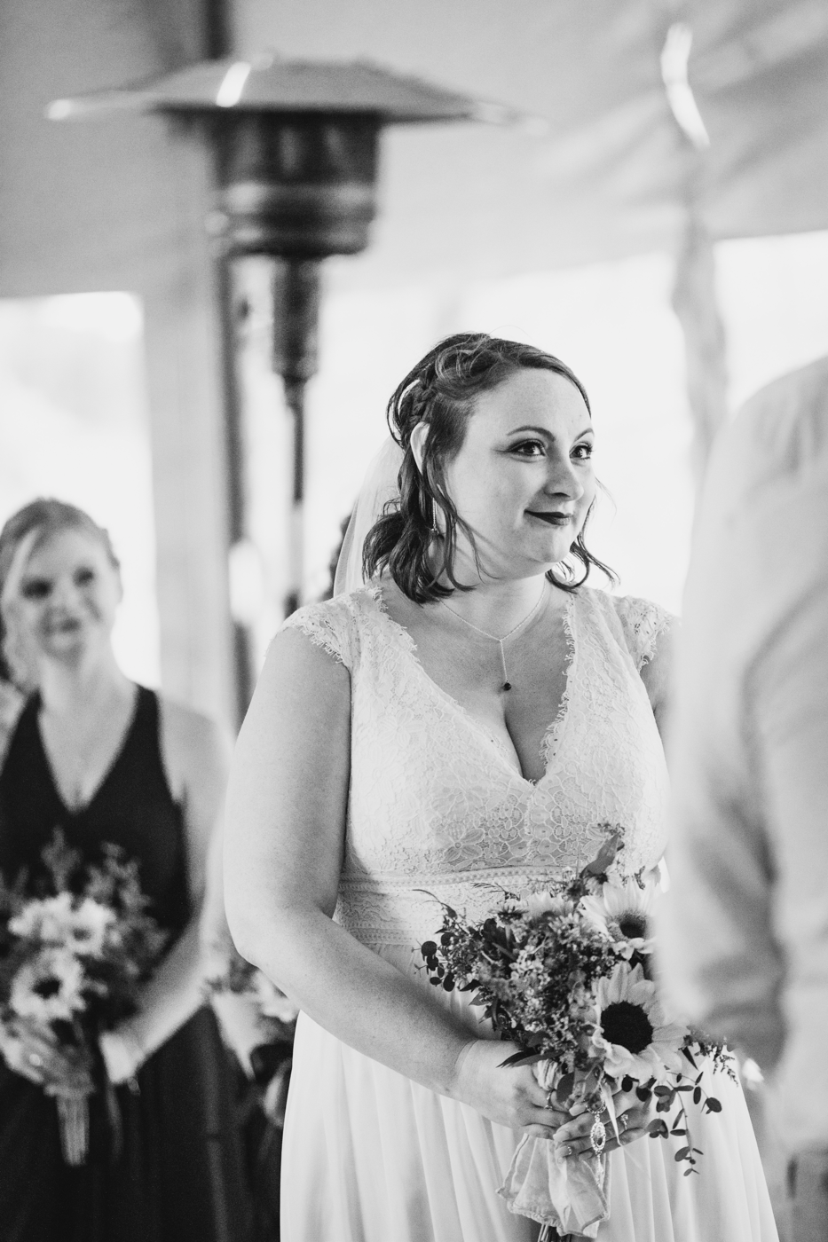  Bride smiles at her fiance during wedding ceremony at Tailwater Lodge in Altmar NY 